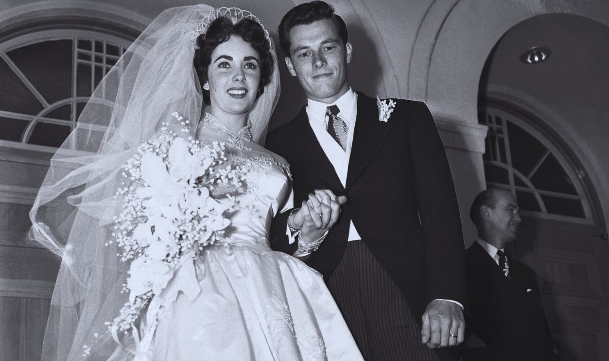 Gettyimages - 514946036, Liz Taylor and Conrad Hilton Jr. (Original Caption) 5/6/1950-Beverly Hills, CA- Mr. and Mrs. Conrad Hilton Jr., pause on the steps of the Church of the Good Shepherd here after their wedding. The bride is the former Elizabeth Taylor, popular Hollywood actress, and the groom is the son of the well-known Hilton Hotel family.