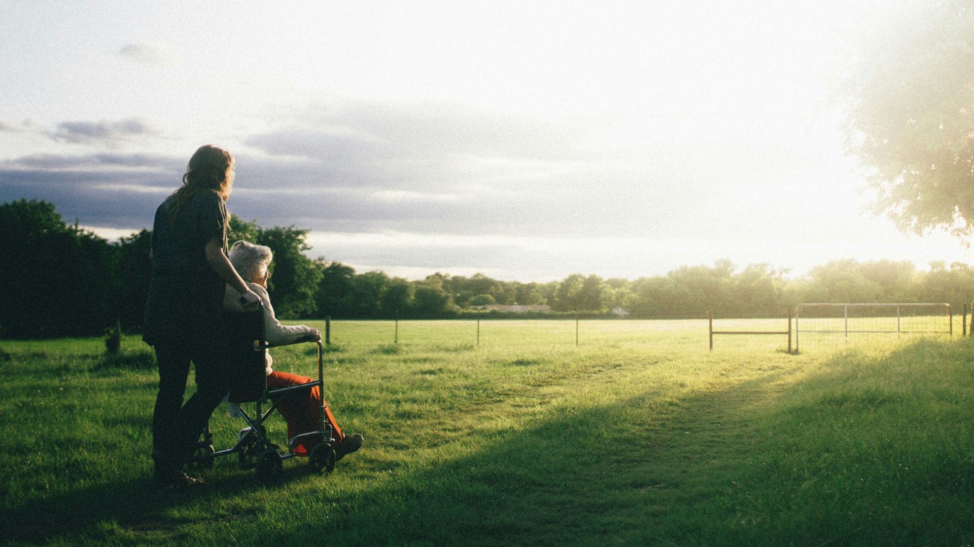 woman standing next to woman riding wheelchair
