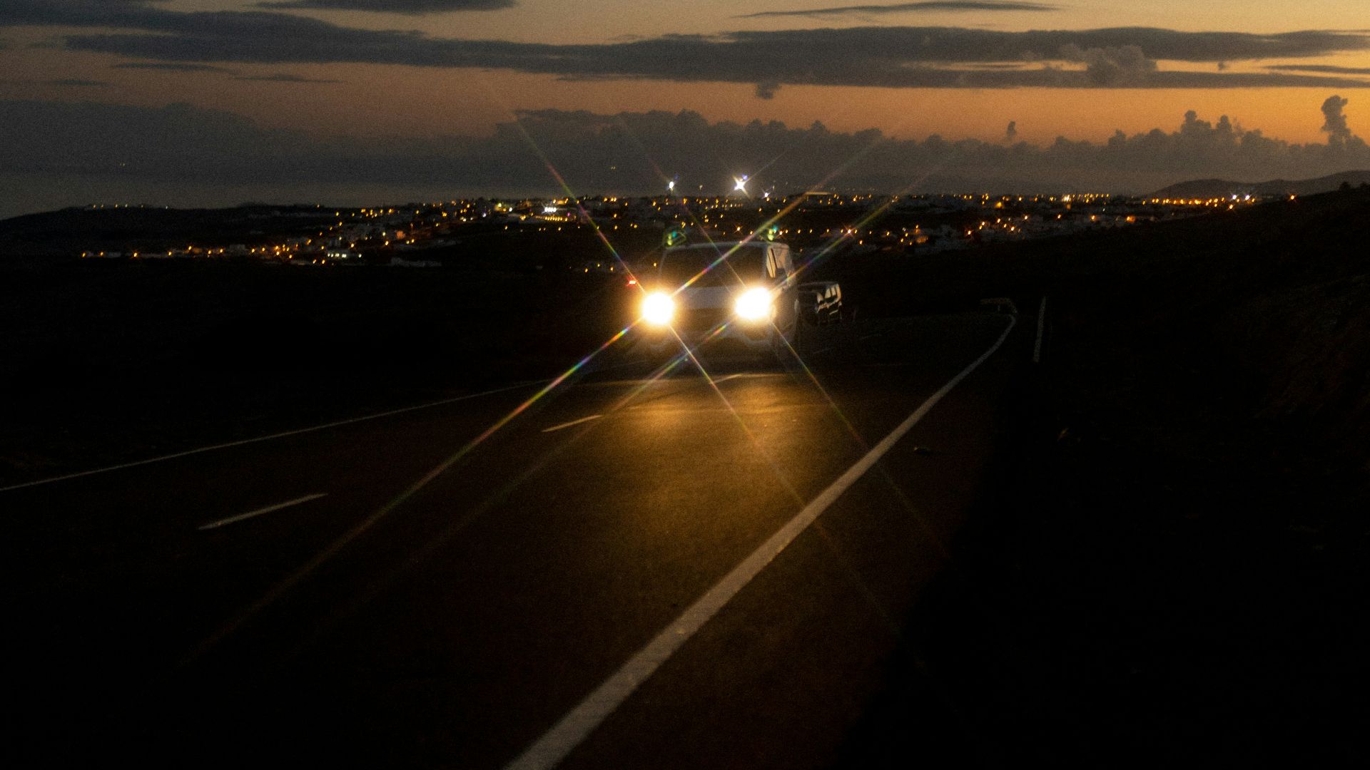 a road with cars on it and a sunset in the background