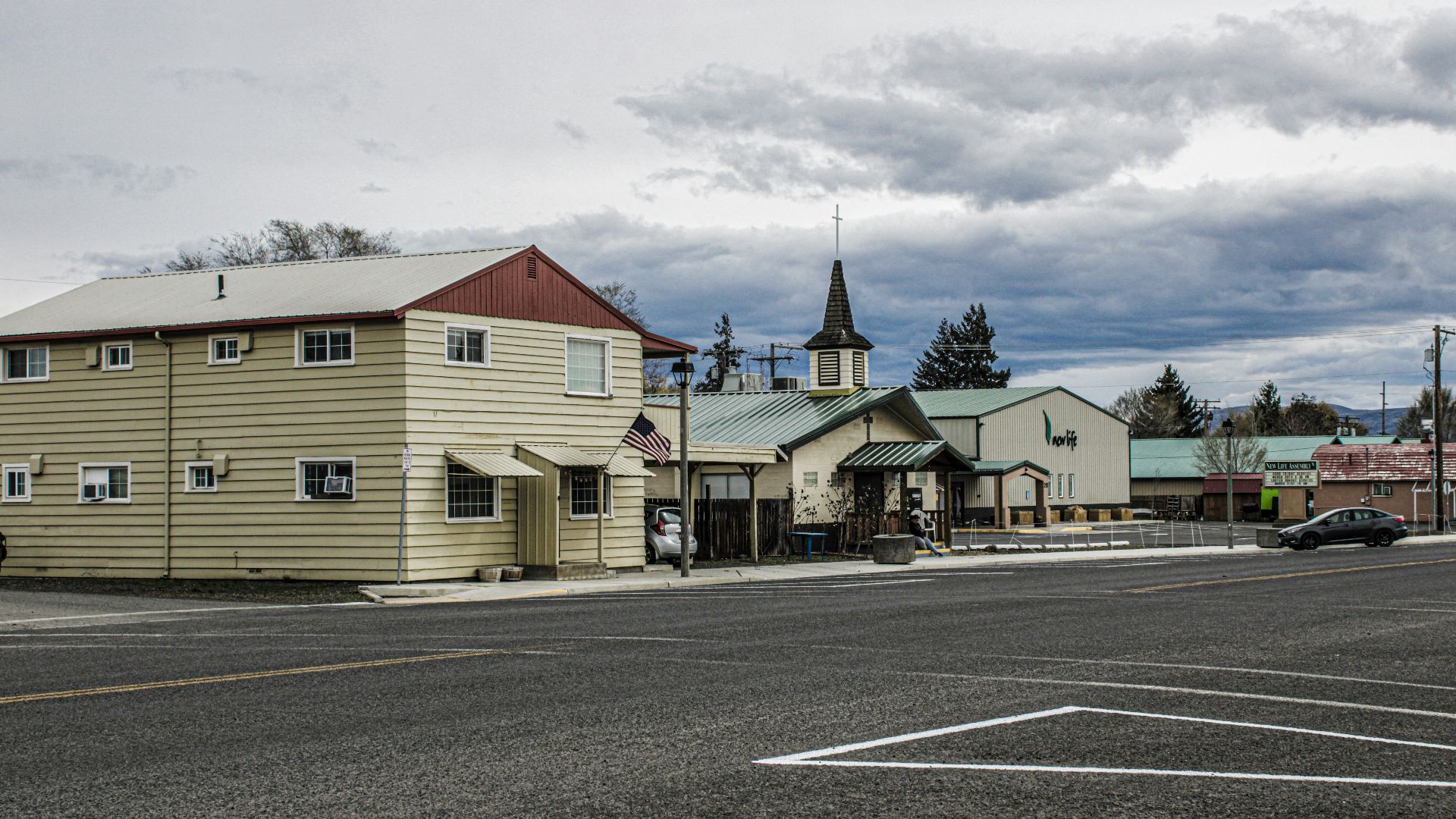 a street with a few buildings and a car parked on the side of the road