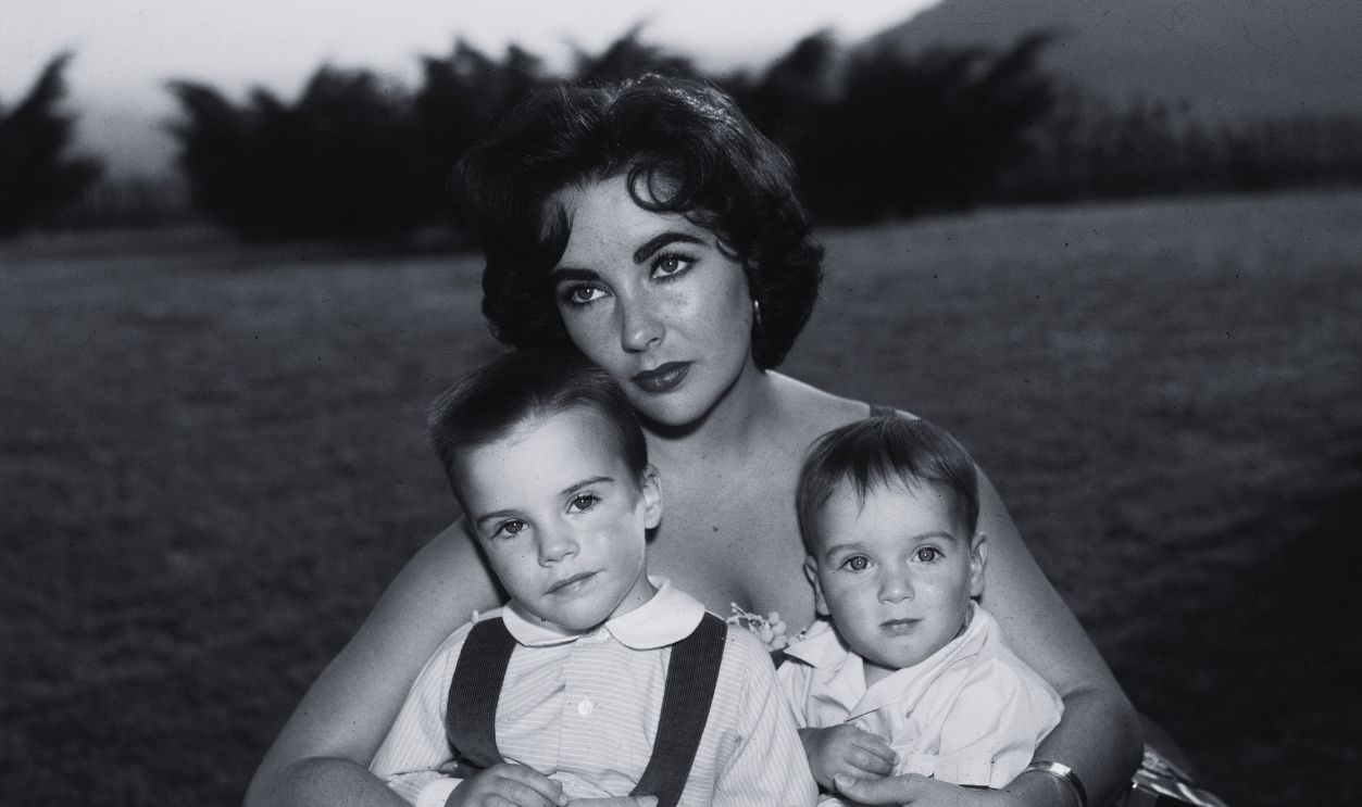 Gettyimages - 2993804, Elizabeth Taylor & Sons British-born actor Elizabeth Taylor sits in a red evening dress with her sons Michael (L) and Christopher Wilding on her lap, mid 1950's.