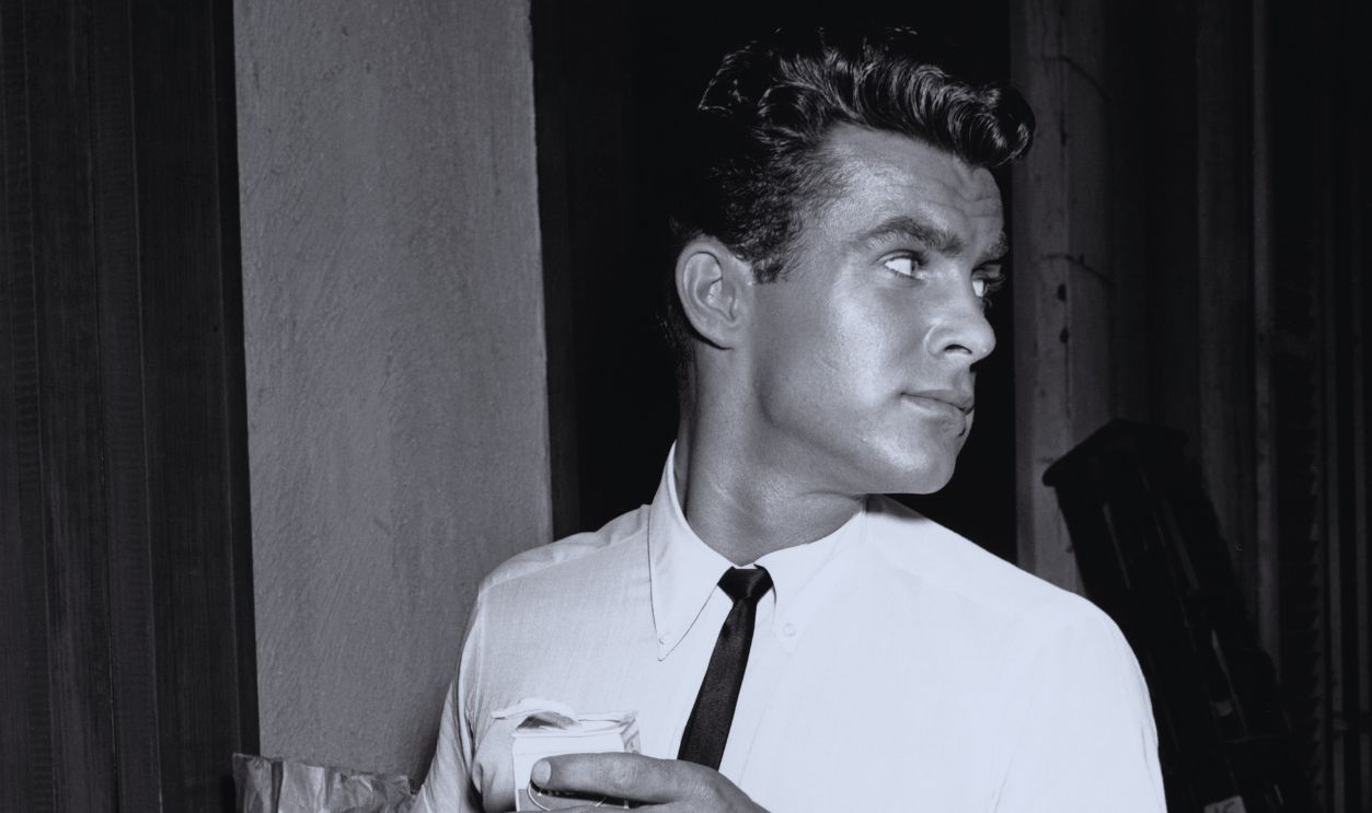 Gettyimages - 1077141476, Robert Conrad American actor Robert Conrad has a snack on the set of 'Secret of the Second Door', an episode of the Warner Bros television detective series 'Hawaiian Eye', 1959.