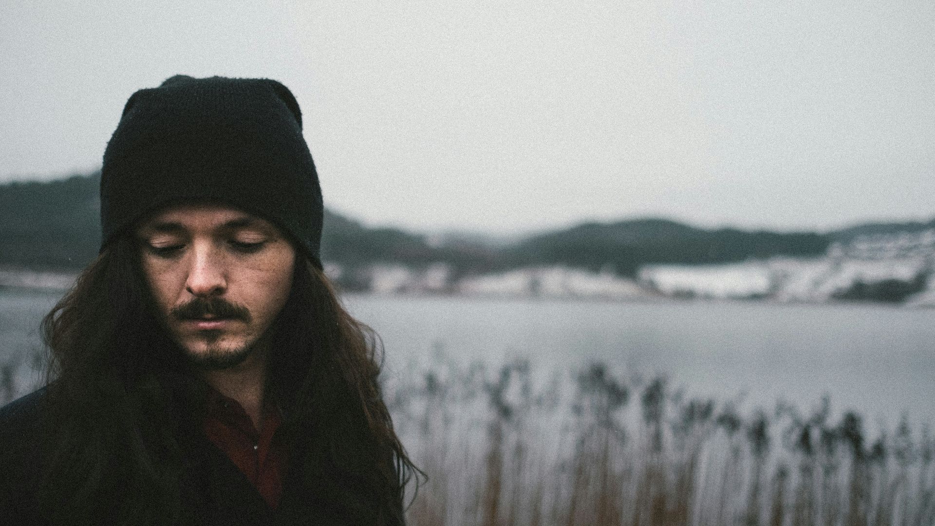 man wearing knit cap near body of water