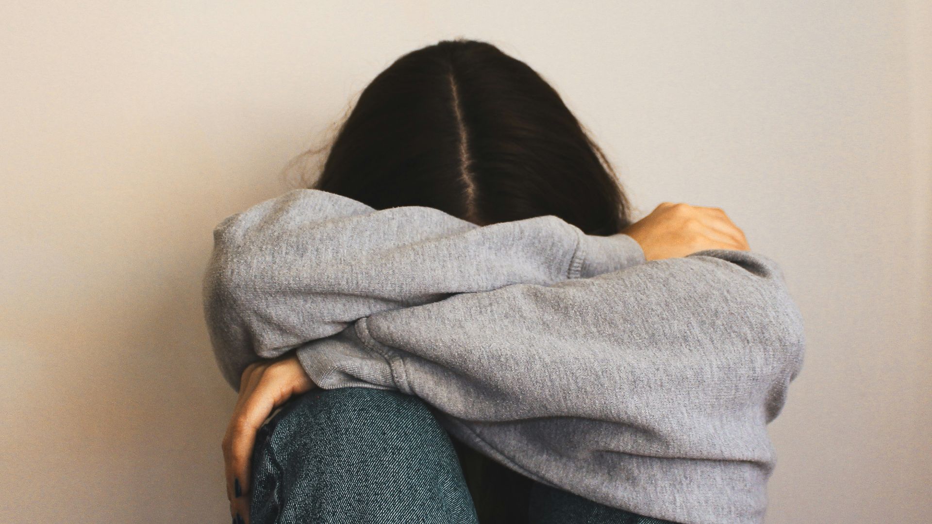 a woman sitting on the floor with her arms wrapped around her head
