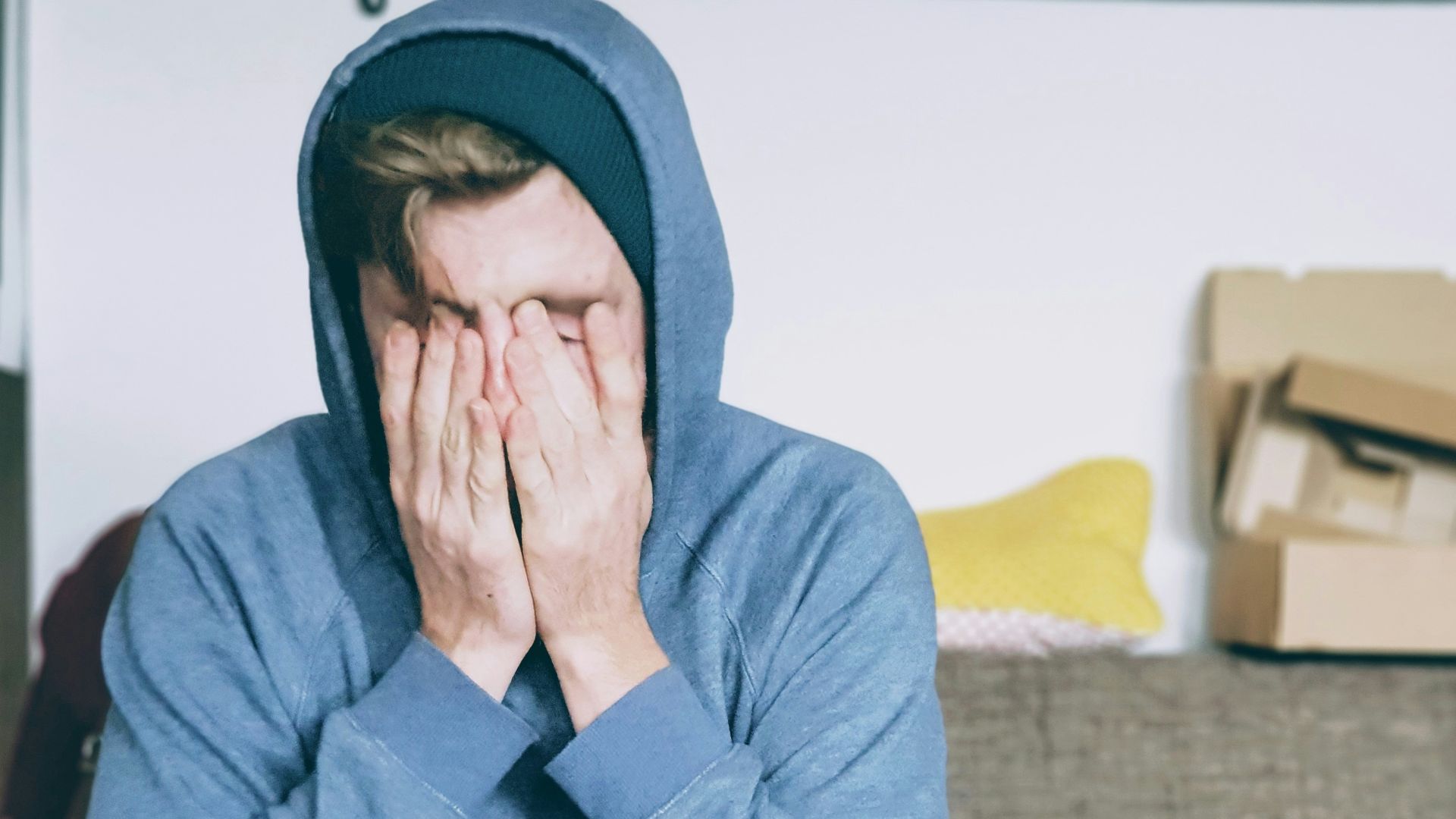 man covering face with both hands while sitting on bench