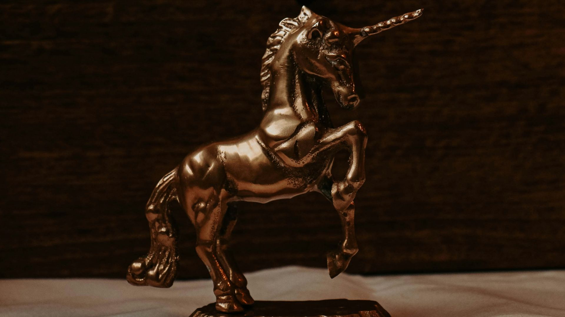 a golden statue of a unicorn on a white sheet