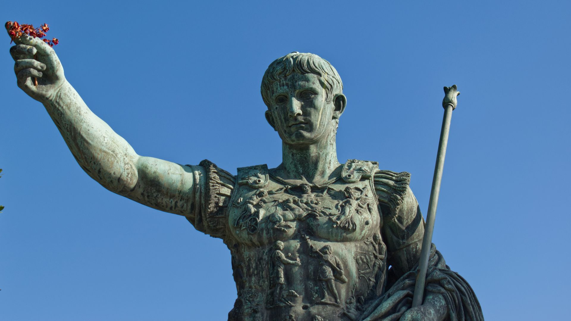man holding stick statue under blue sky during daytime