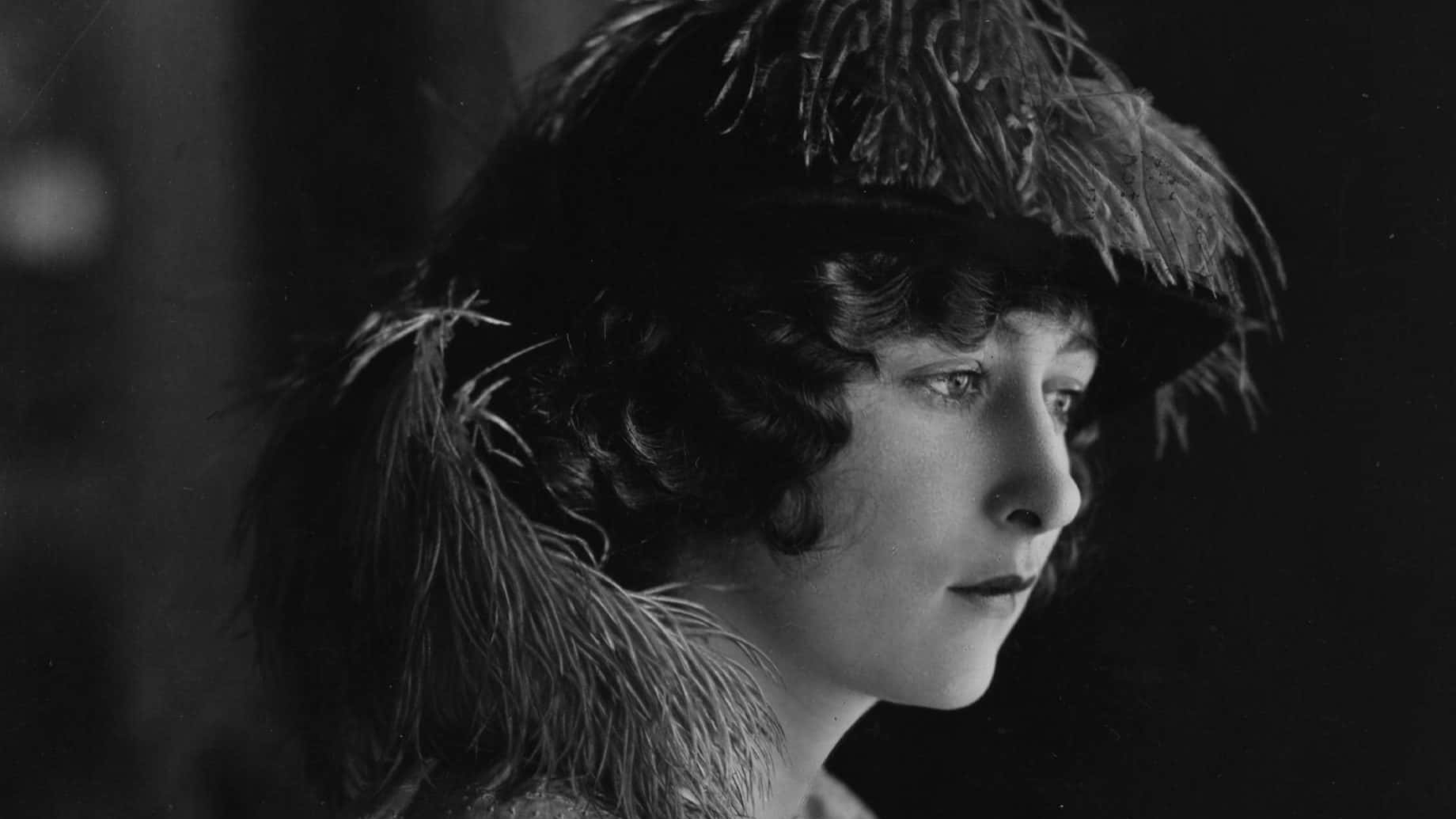 Mildred Harris wearing a hat and black dress