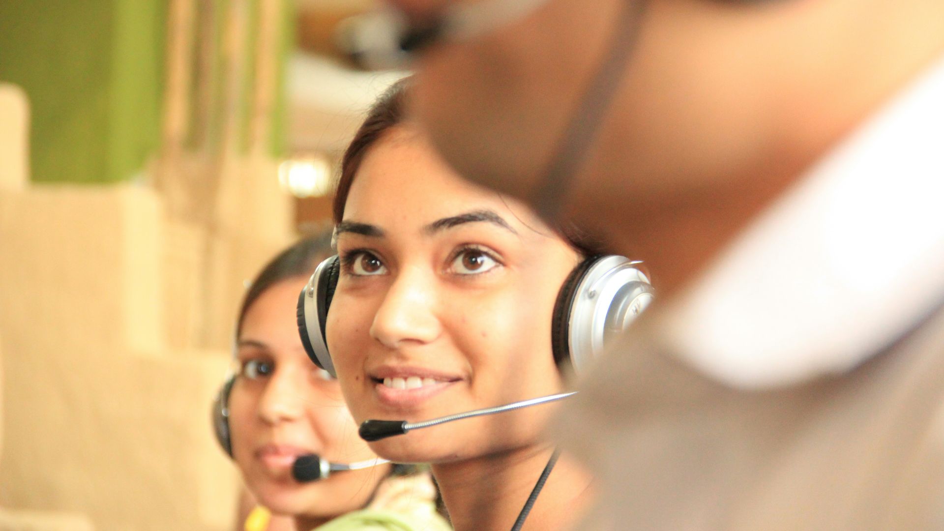 woman in black headphones holding black and silver headphones