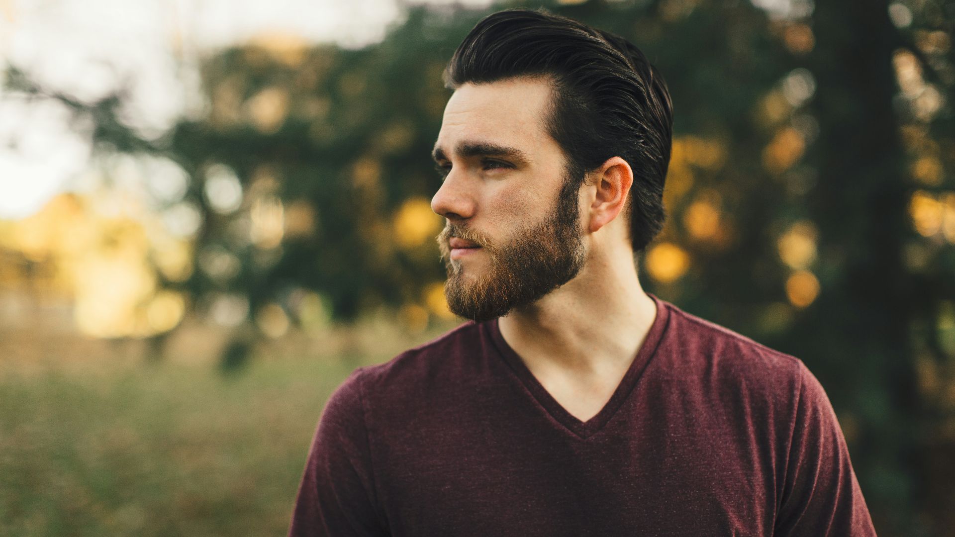 man wearing maroon V-neck t-shirt in forest