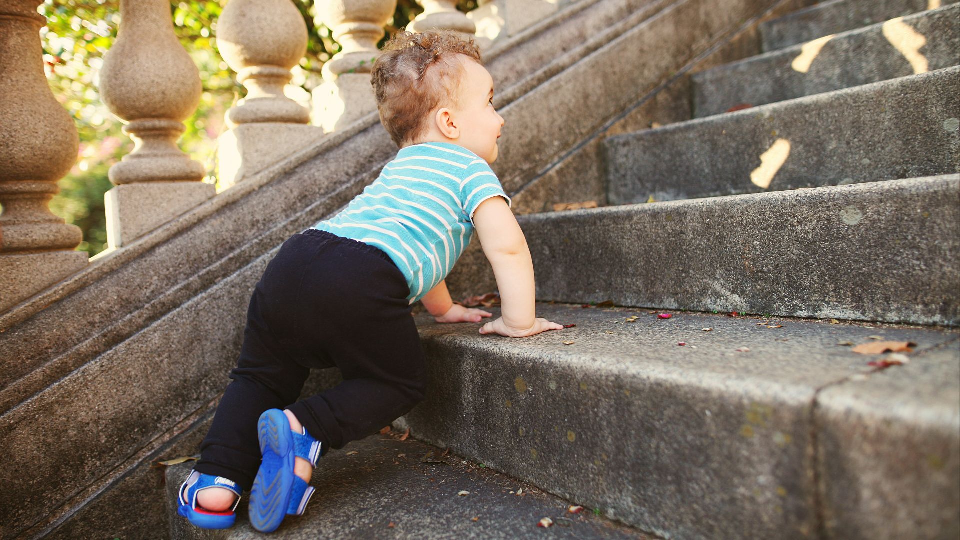boy in green and white striped t-shirt and black pants sitting on concrete stairs during