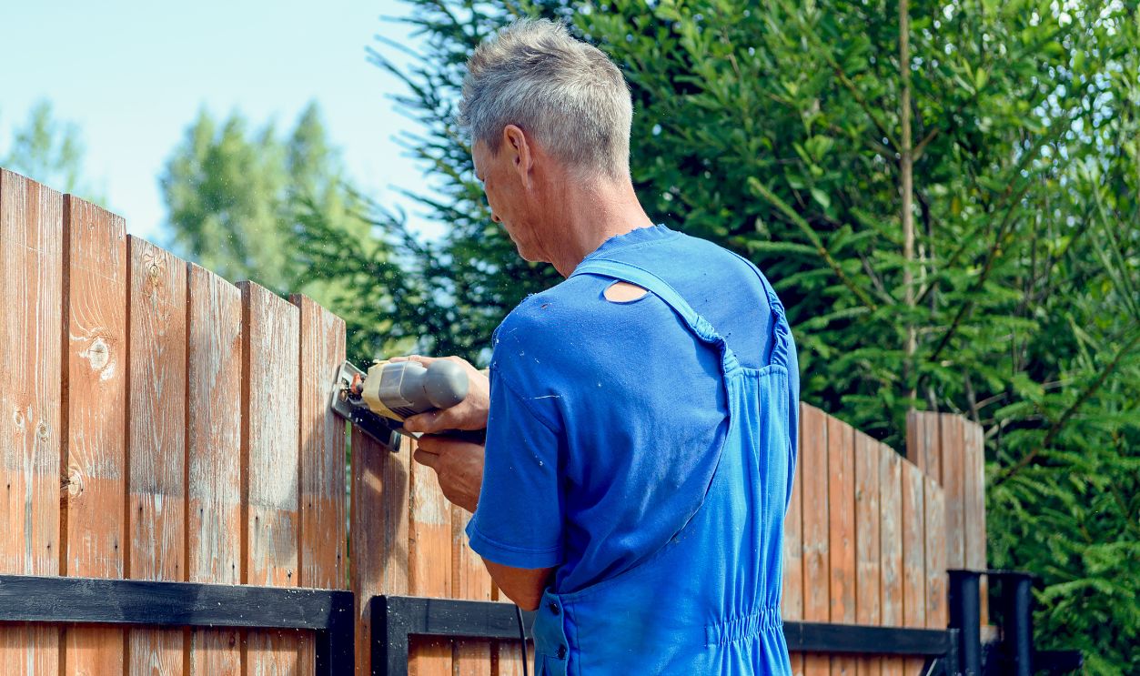Close-up of the process of cutting the fence with a jigsaw. A man aligns the fence with a jig saw on a country plot