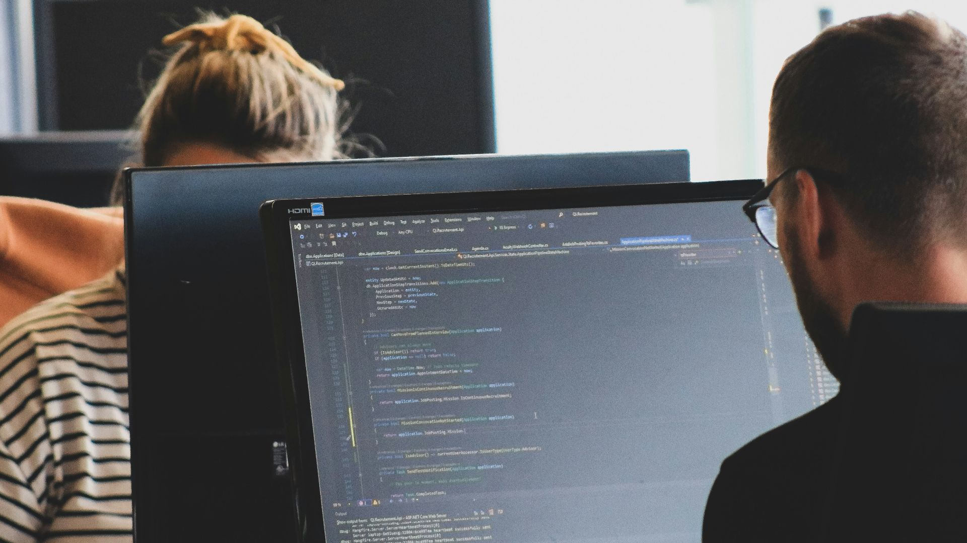woman in black shirt sitting beside black flat screen computer monitor