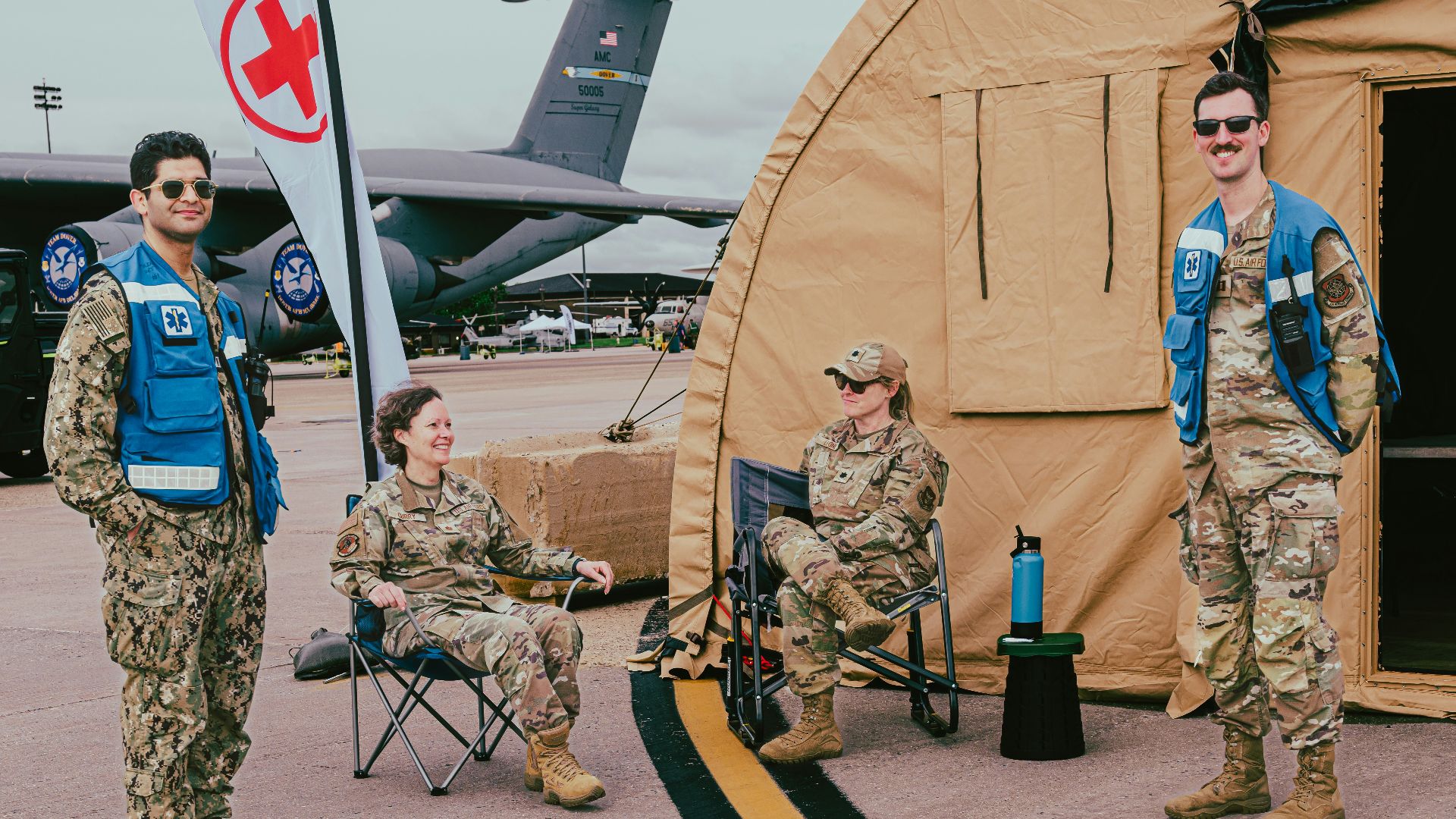Military personnel pose near a medical tent and plane.