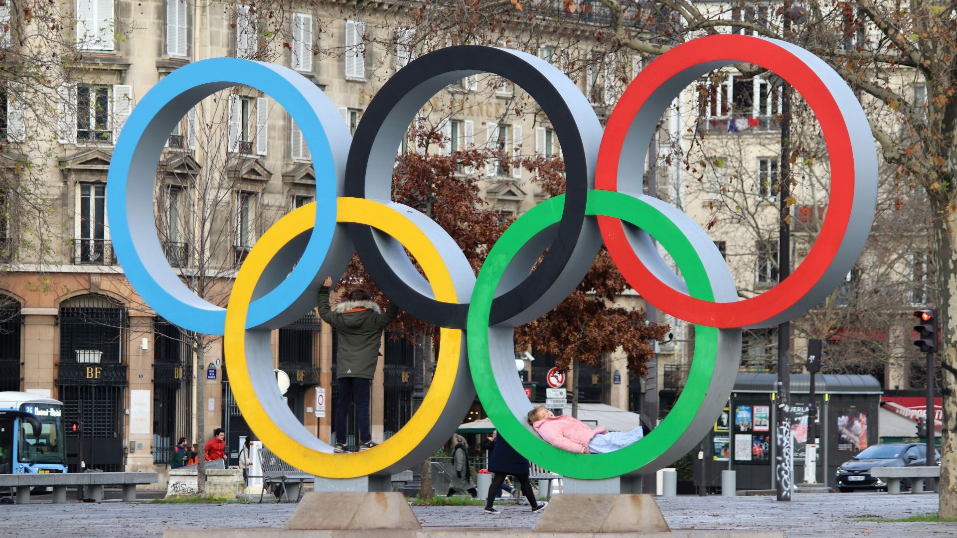 The olympic rings stand in a city square.
