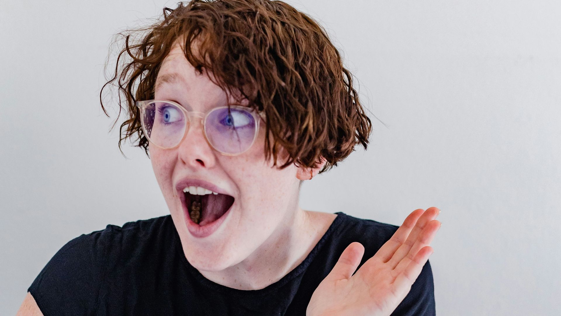 a woman with curly hair and glasses making a funny face