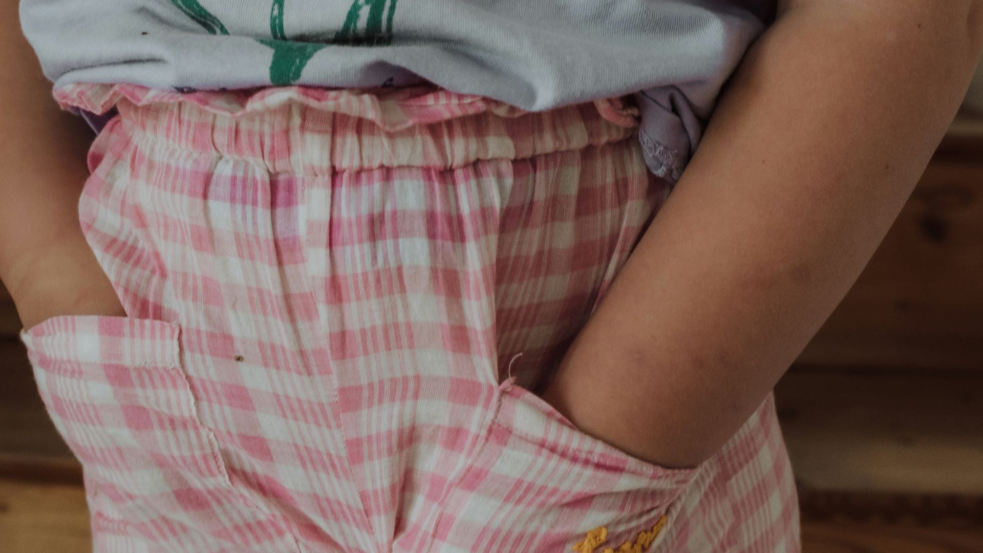 a little girl standing with her hands in her pockets