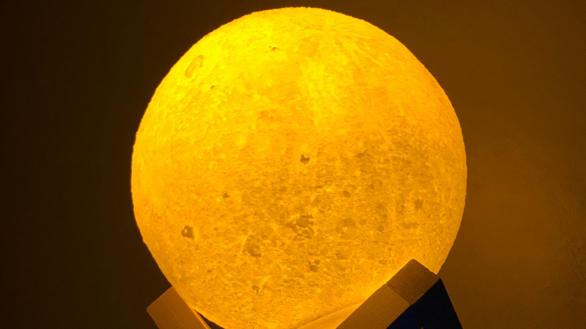 a yellow moon lamp sitting on top of a wooden stand