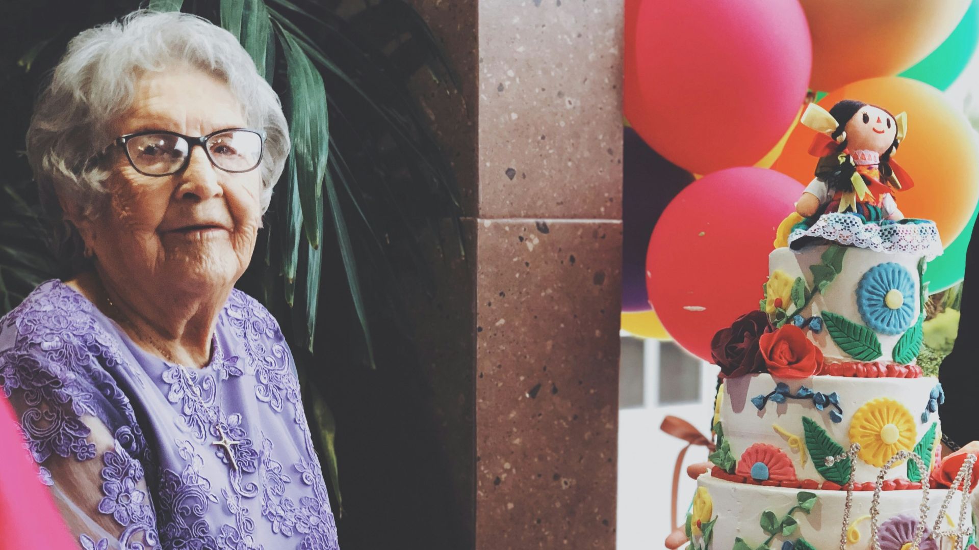 woman wearing purple floral long-sleeved dress besides 4-layer cake