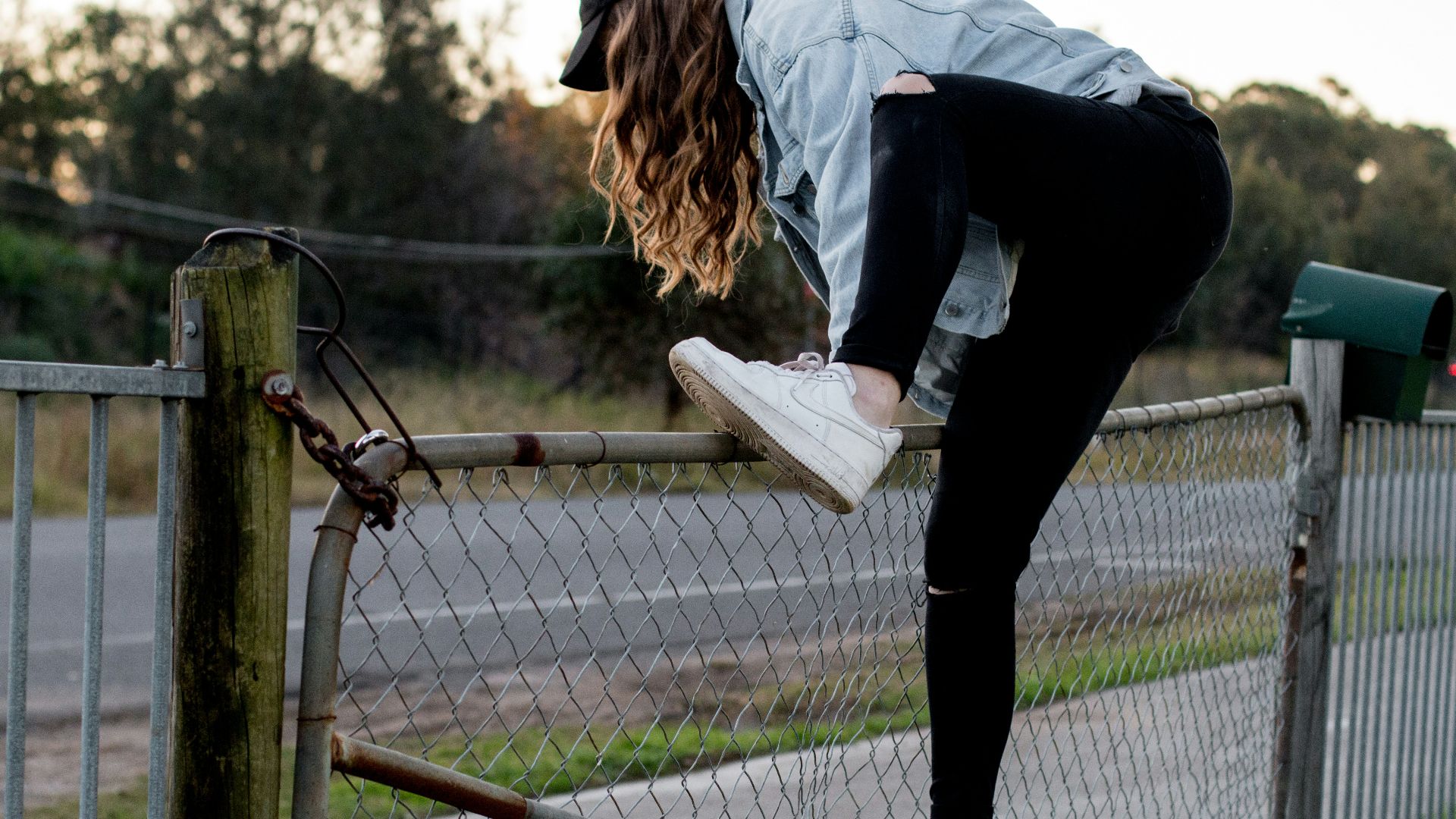 woman climbing over fence