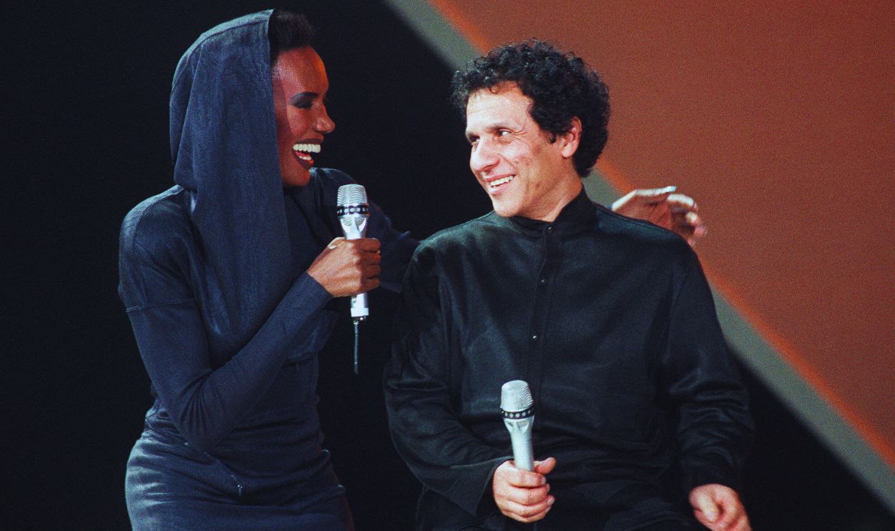 Gettyimages - 1182569976, MEDIA-TELEVISION-JONES-ALAIA American singer Grace Jones speaks with Tunisian fashion stylist Azzedine Alaia on January 30, 1987, during the recording of the television show Grand Public-UAP presented by host Patrick Sabatier at the Palais omnisports de Bercy in Paris. 