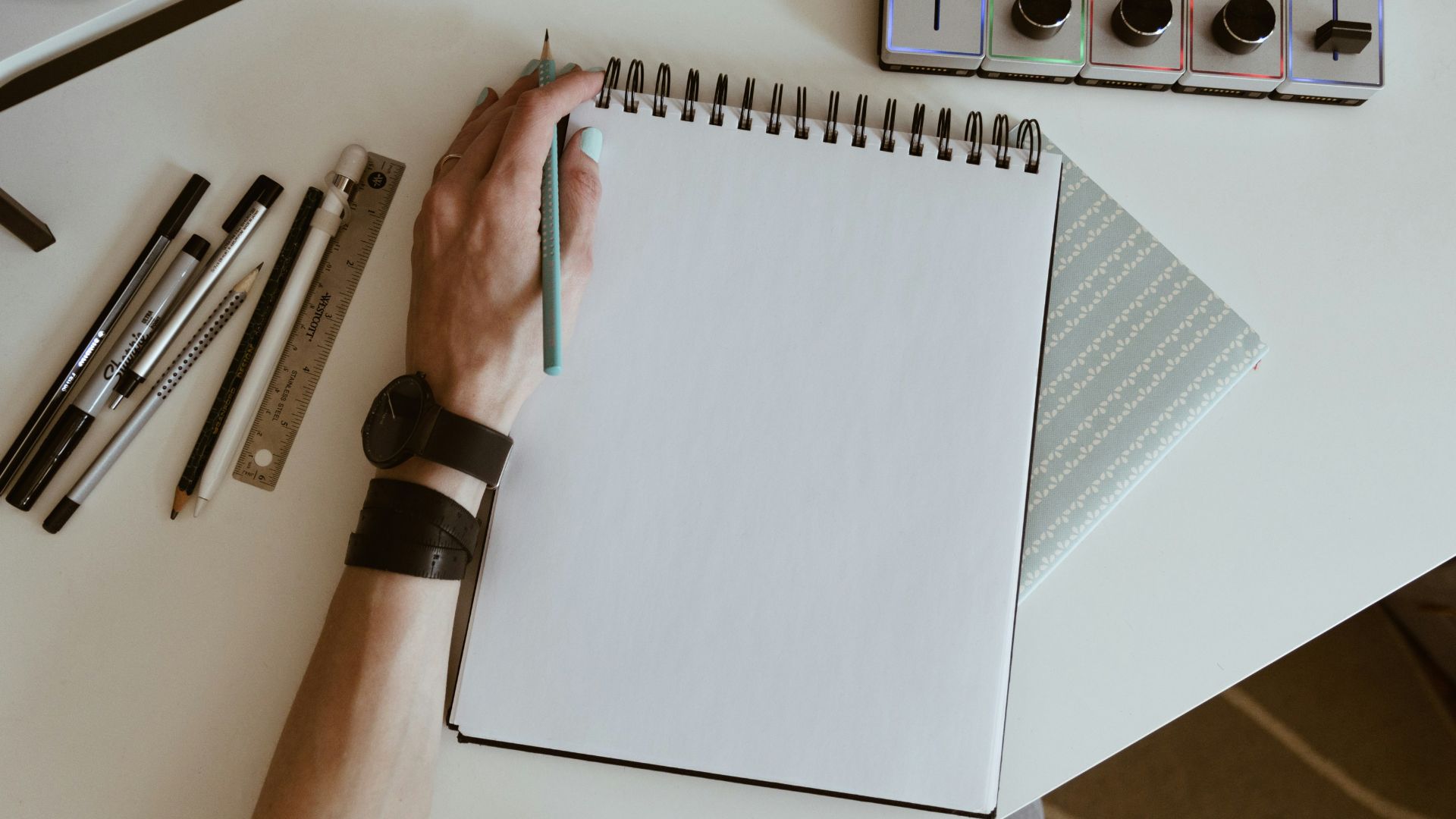 white spiral book with pens and watches