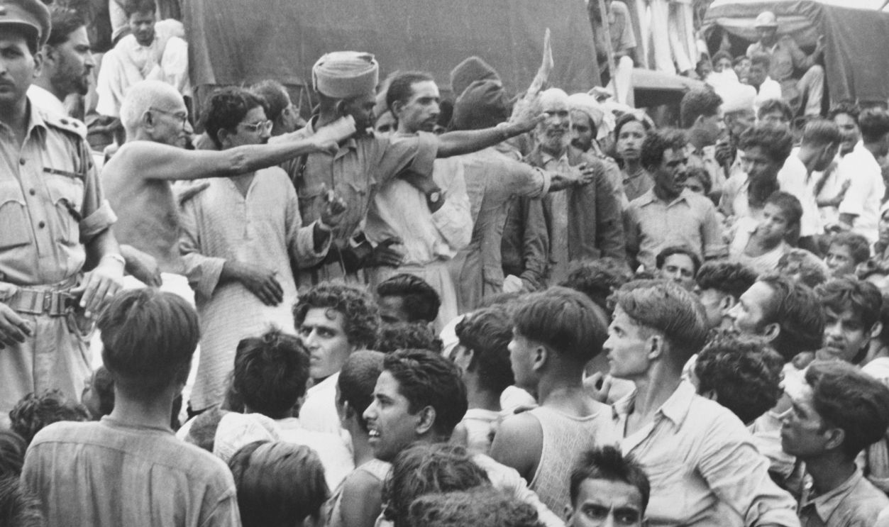 New Delhi, India: Gandhi Visits Muslim Refugees. Mohandas K. Gandhi (Center, bare chest), Hindu Spiritual Leader, waves to the Muslim crowd on his visit to the Purana Qila camp where 50,000 Muslim Refugees await transportation to Pakistan. The Muslims have pinned their hopes on the personal efforts of Mr. Gandhi to bring to an end the rampage of massacre, rape, and arson between Hindus and Muslims.