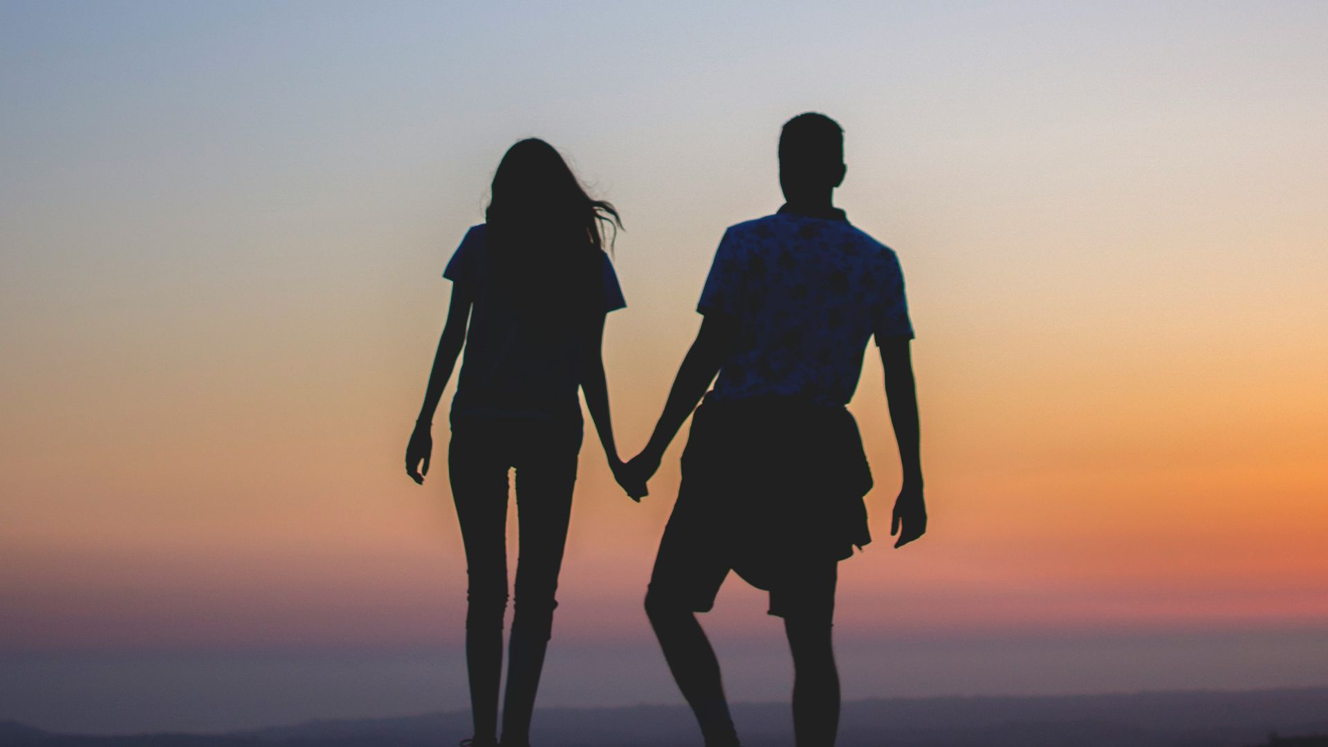 man and woman holding hands in silhouette photography