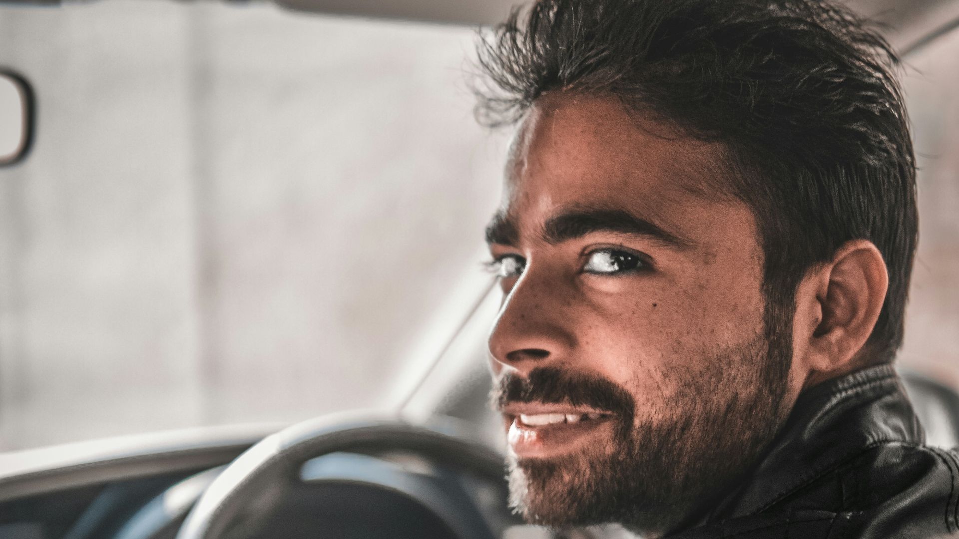 man in black leather jacket sitting on blue car seat