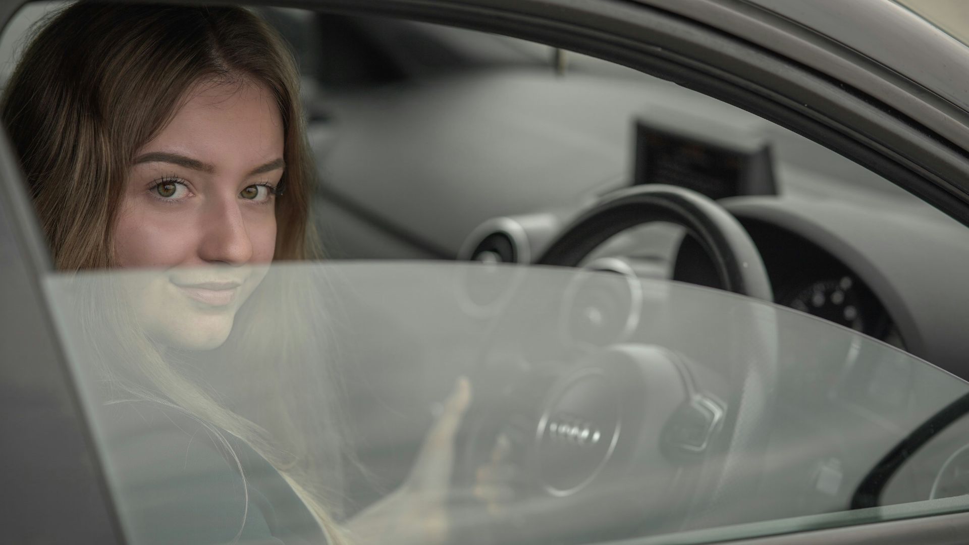 a woman sitting in a car holding a steering wheel