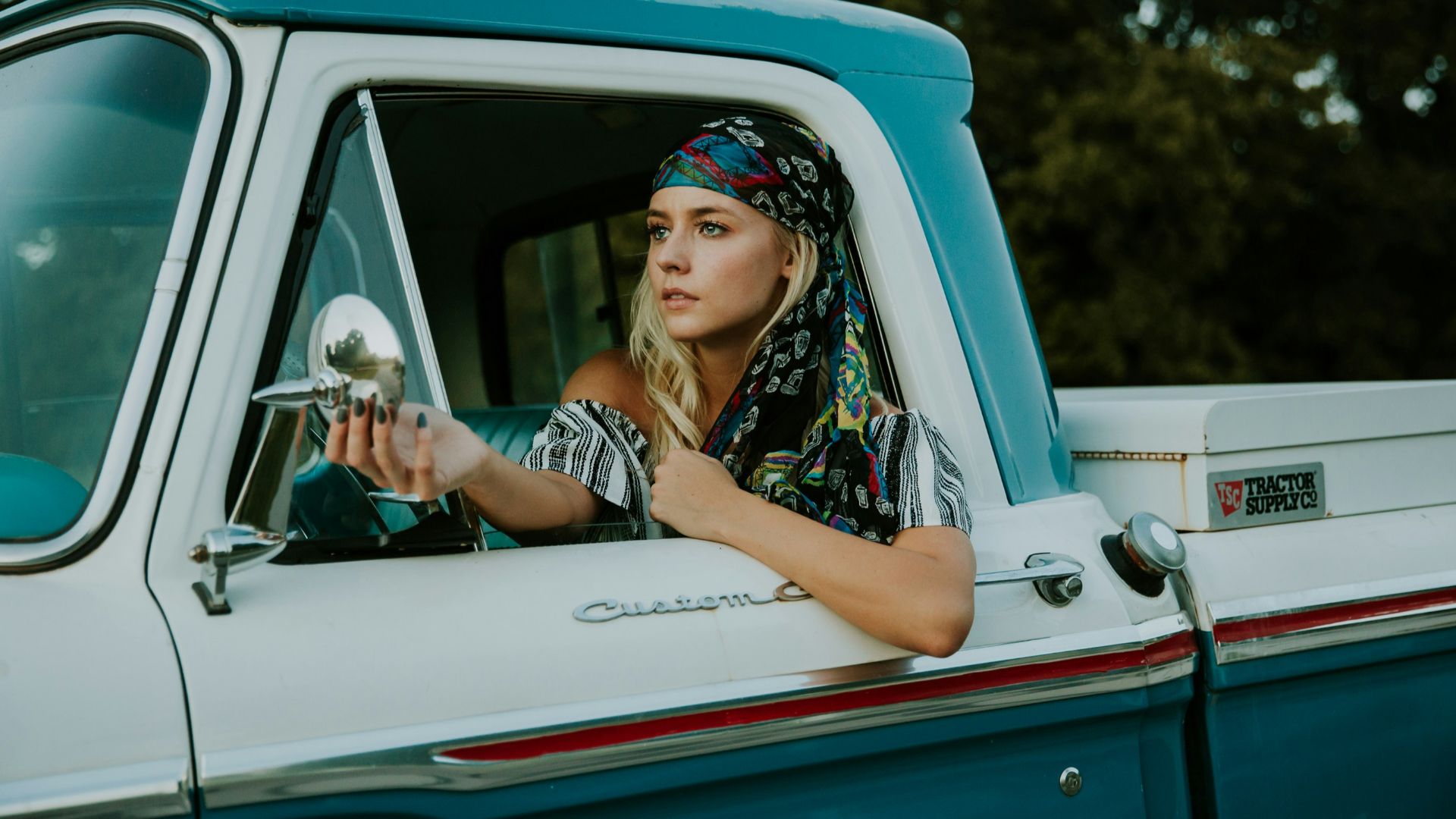 photography of woman holding side mirror in white and green 2-door pickup truck