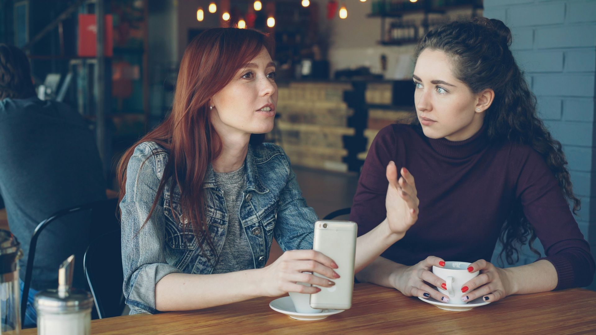 Two women converse at a cafe.