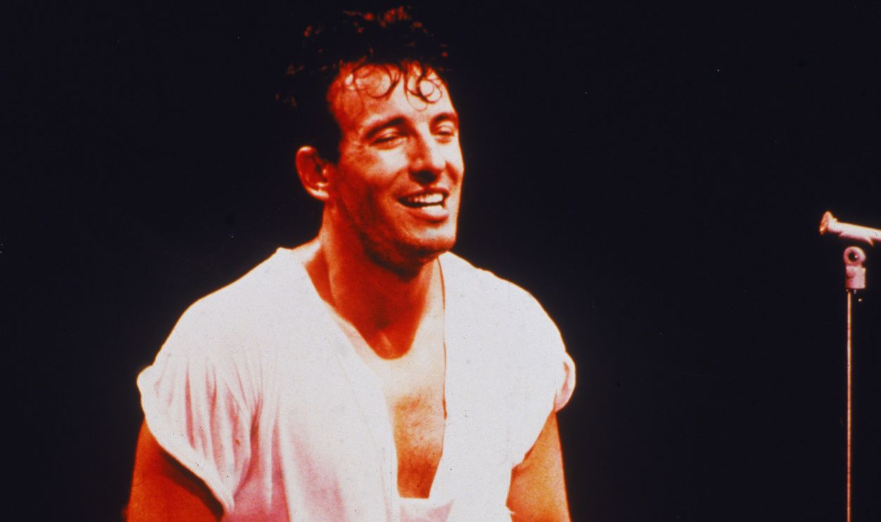 Gettyimages - 3179823, Bruce Springsteen Holds Guitar On Stage American rock singer and songwriter Bruce Springsteen stands onstage, holding an electric guitar at his side during a concert, 1980s.