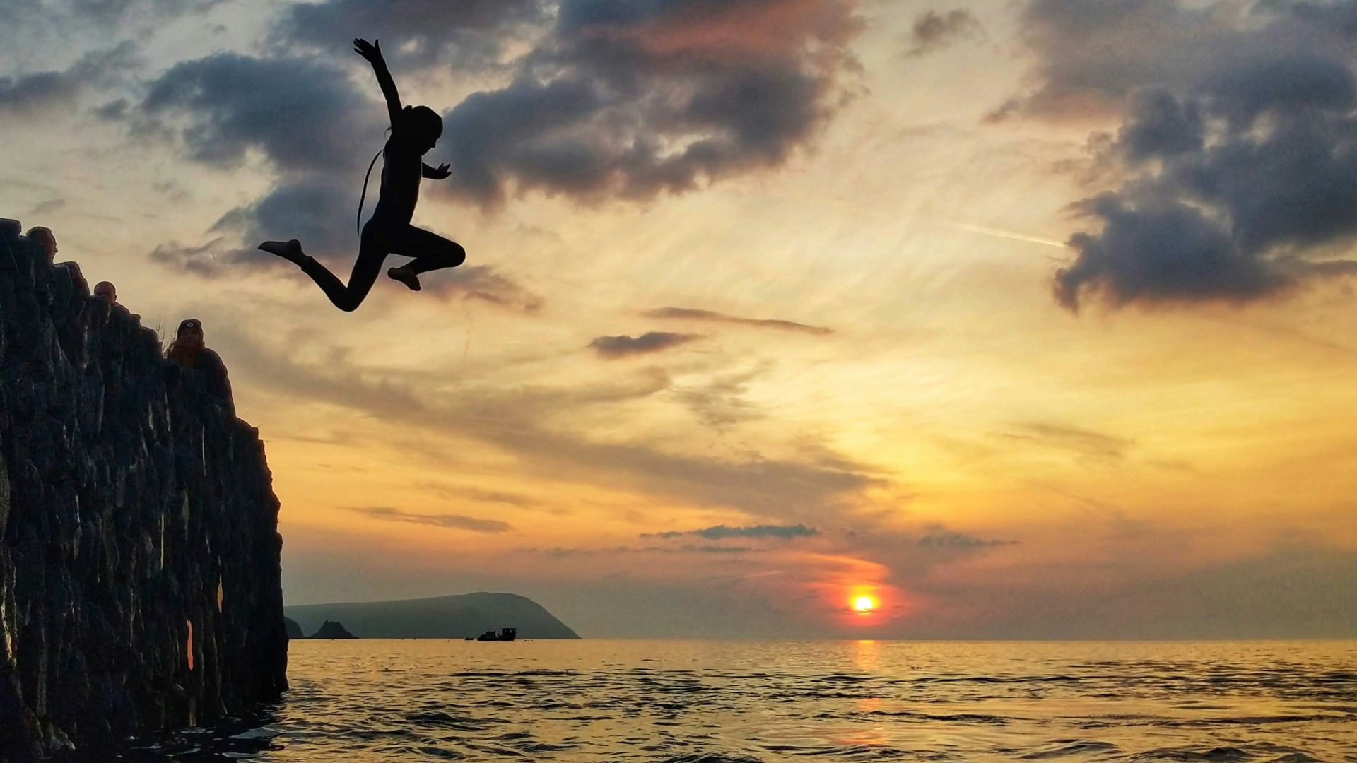 silhouette of man jumping on sea during sunset