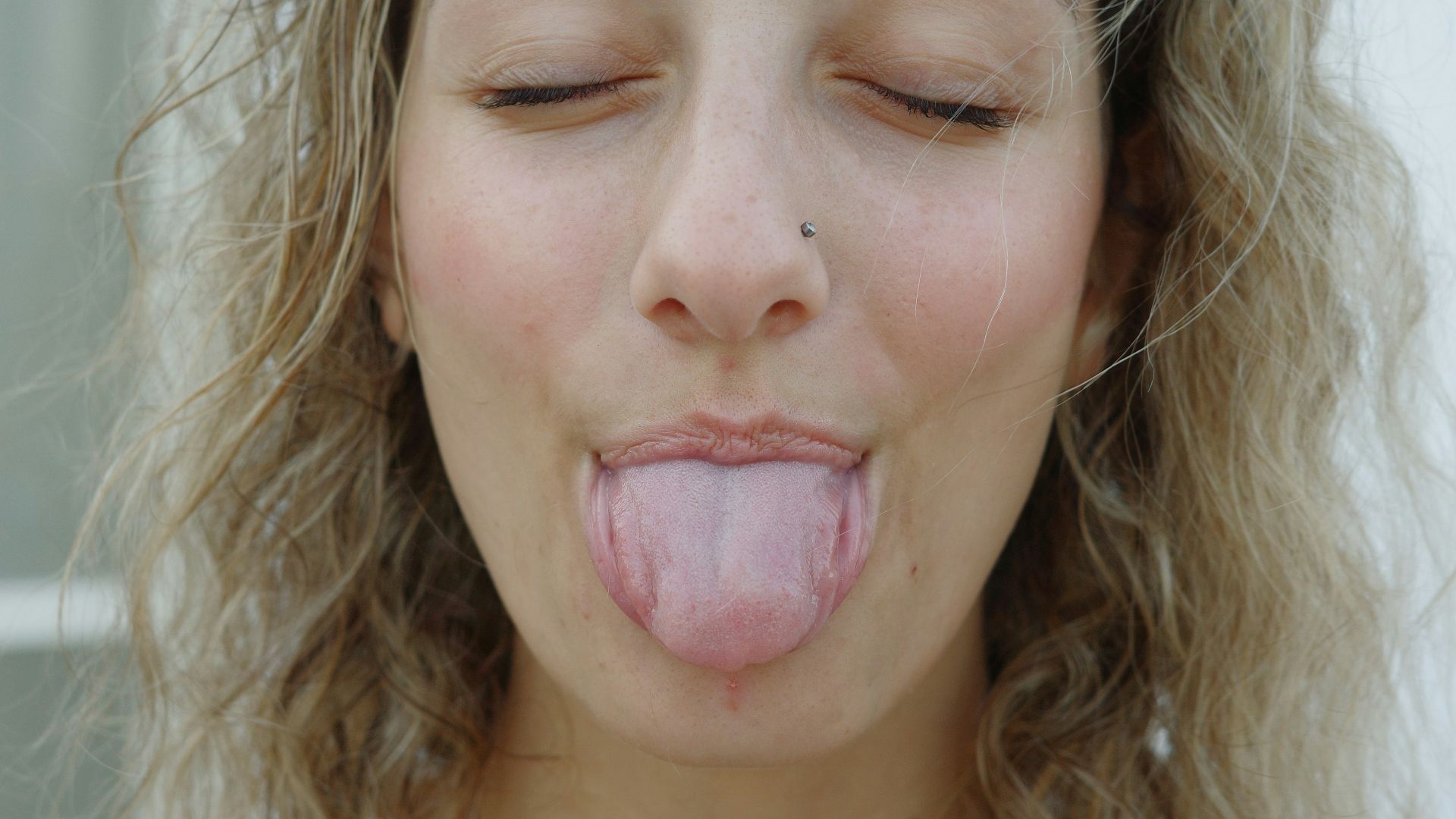 A woman sticking her tongue out with her eyes closed