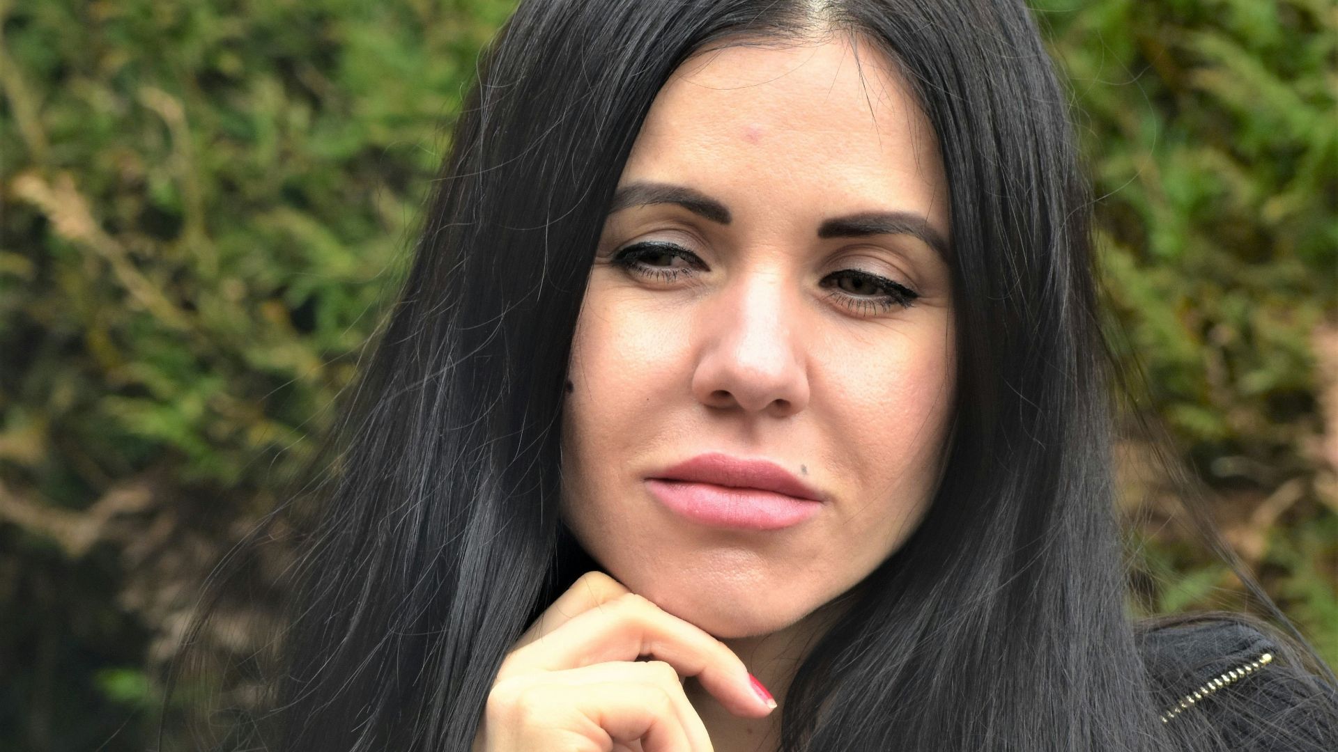A woman with long black hair is posing for a picture