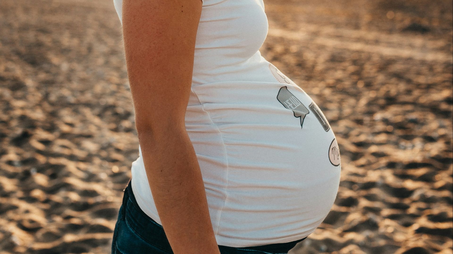 pregnant woman standing on sand