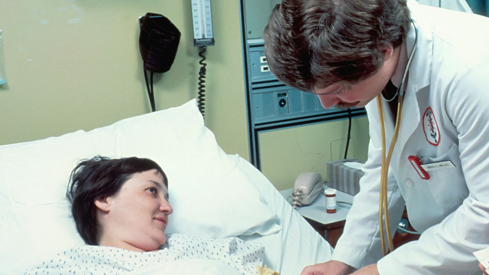 a woman laying in a hospital bed next to a man