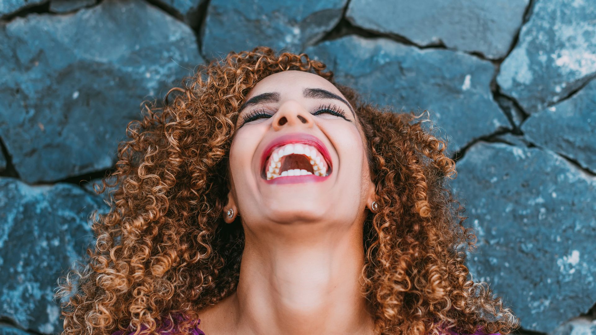 a woman with curly hair laughing and looking up