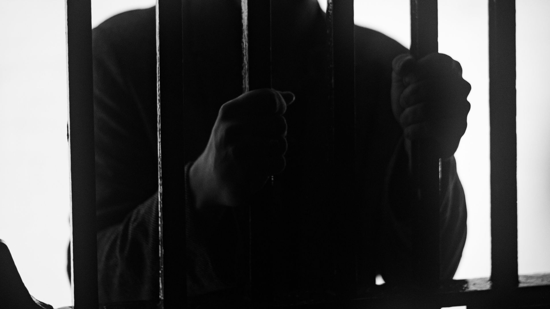 a man standing behind bars in a jail cell