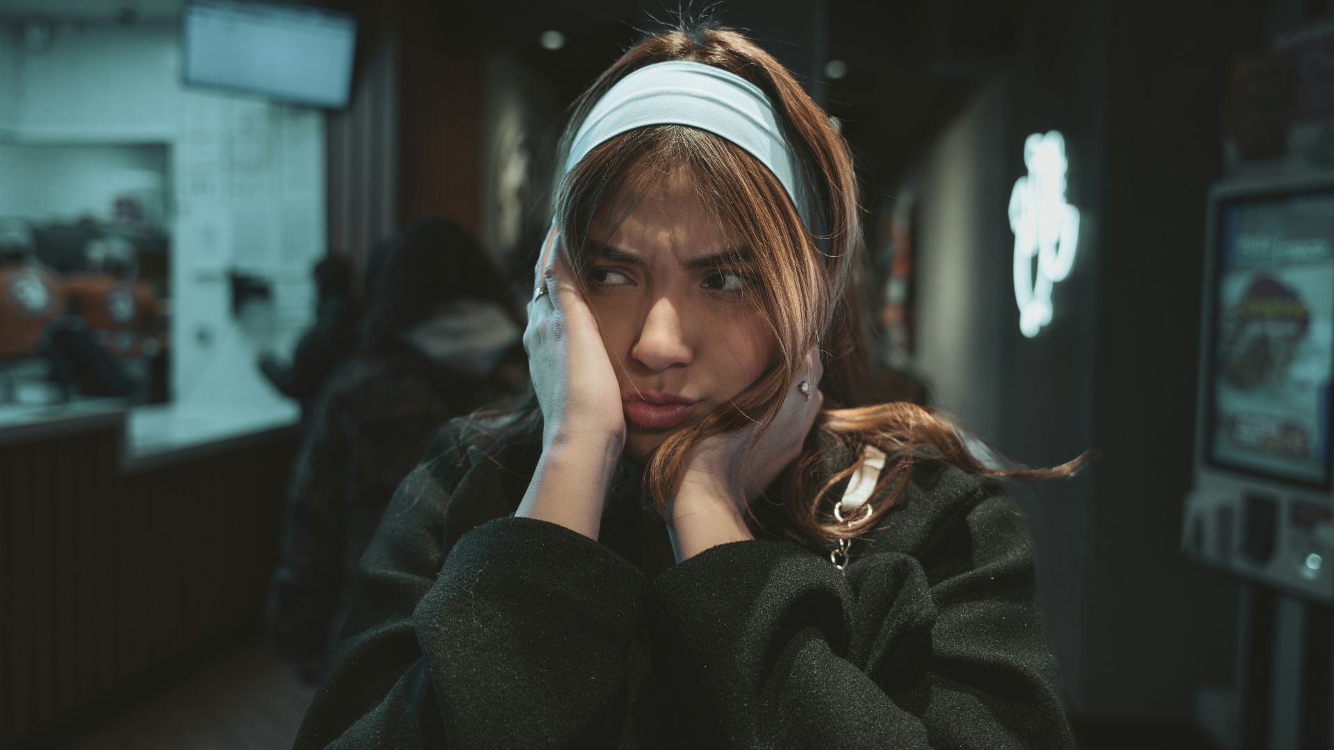 a woman with a headband on talking on a cell phone