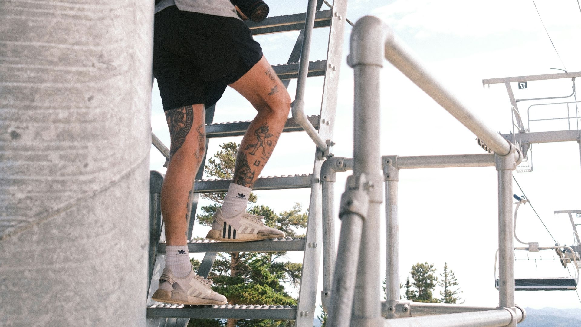 A person climbs a metal ladder outdoors.