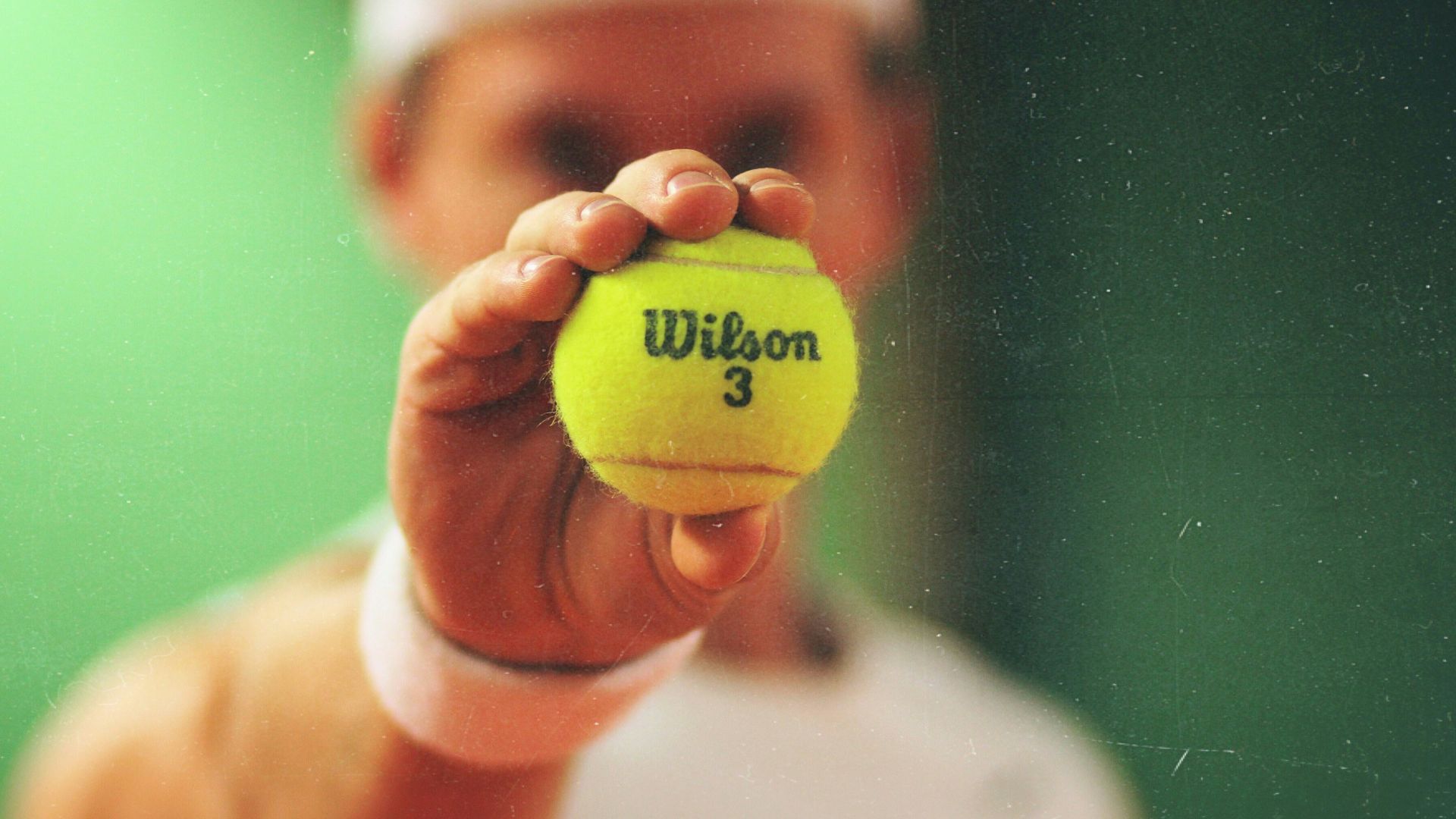 person holding green Wilson tennis ball