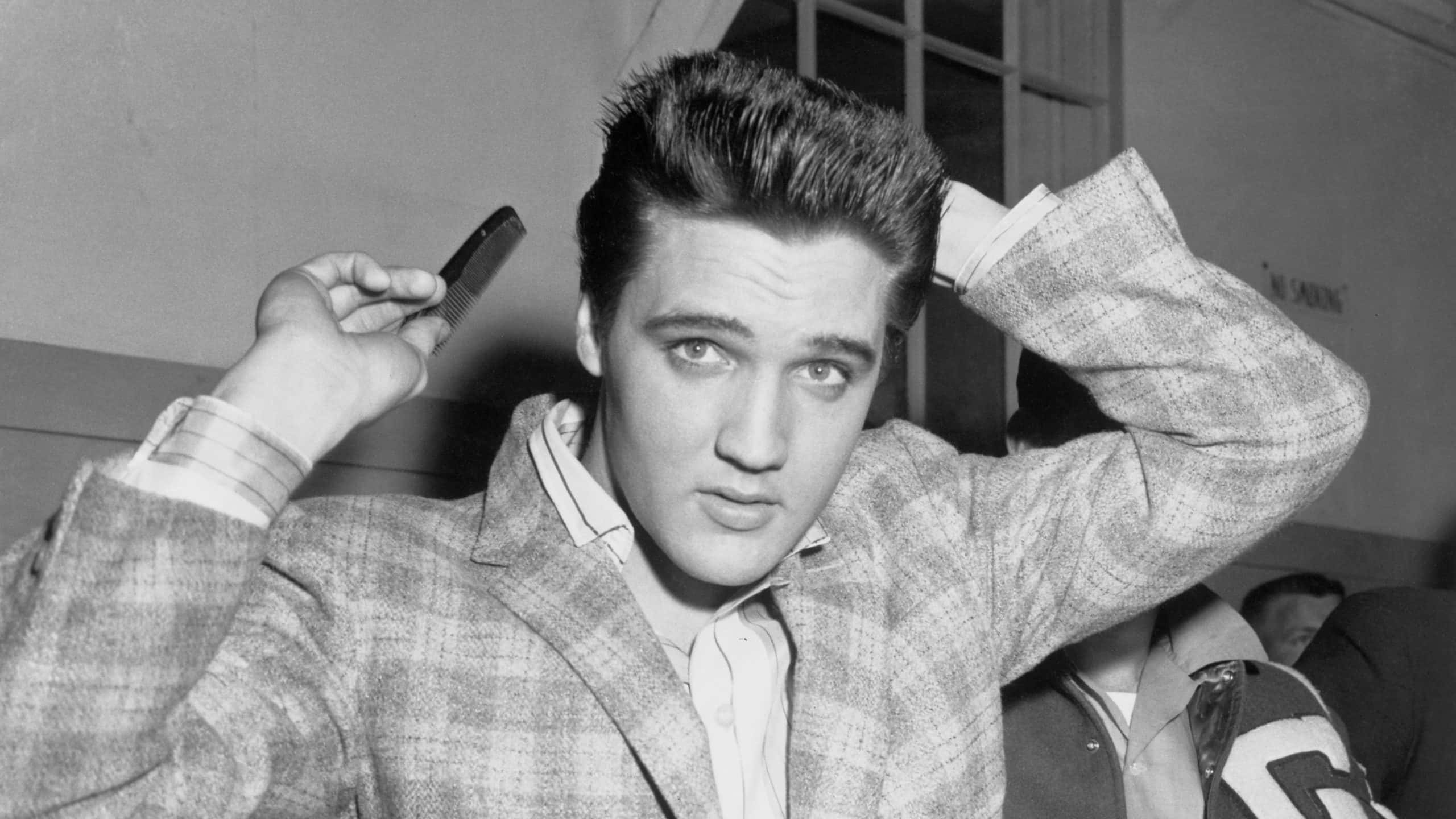 Elvis Presley runs a comb through his famous tresses.