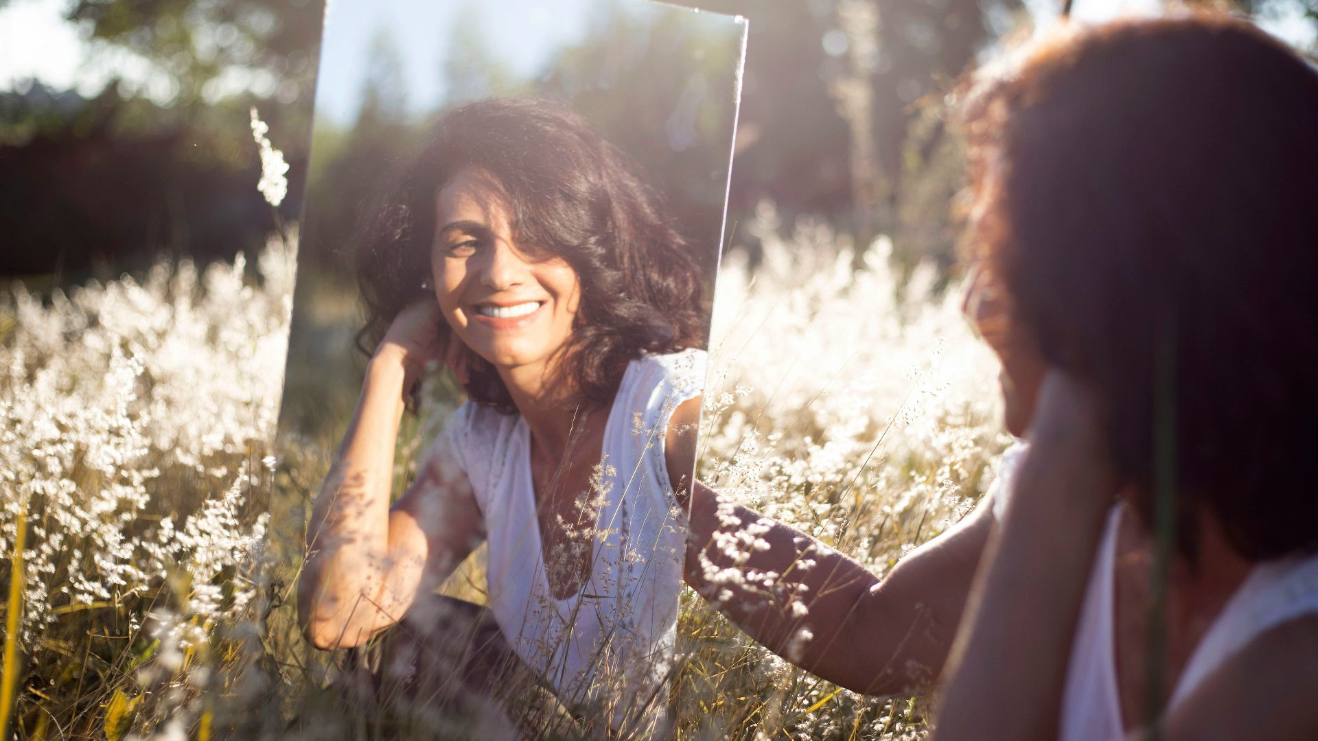 woman in blue and white floral shirt holding her face