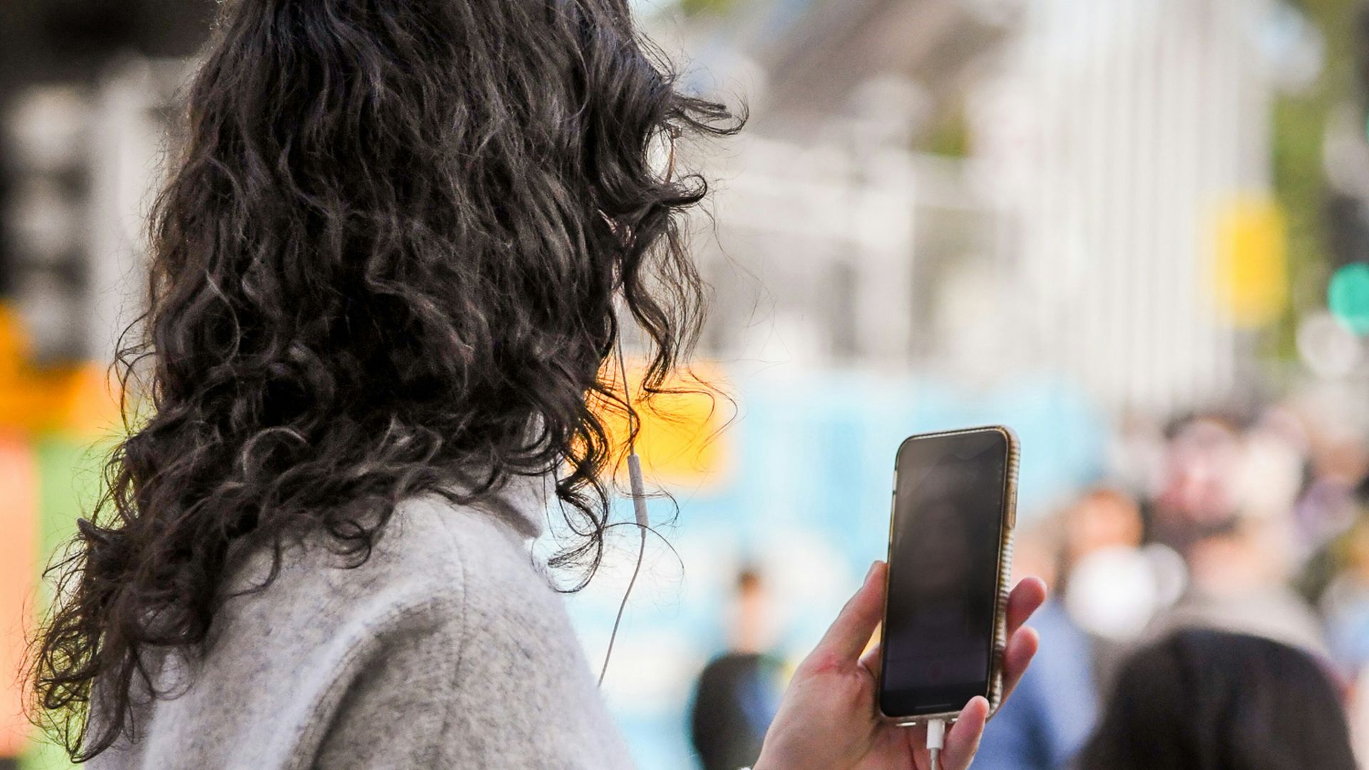 woman in gray sweater holding smartphone