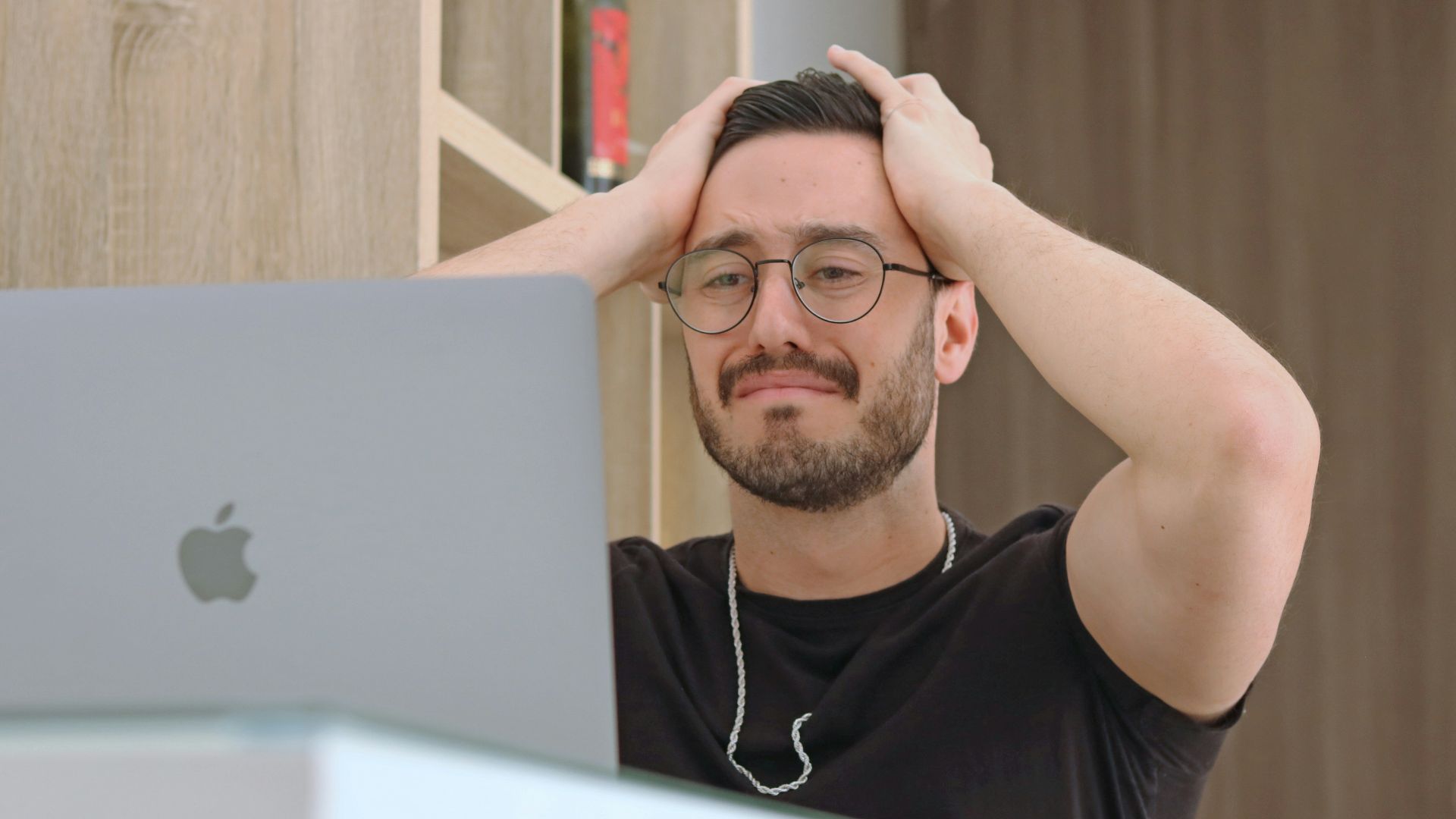a man with glasses is looking at a laptop