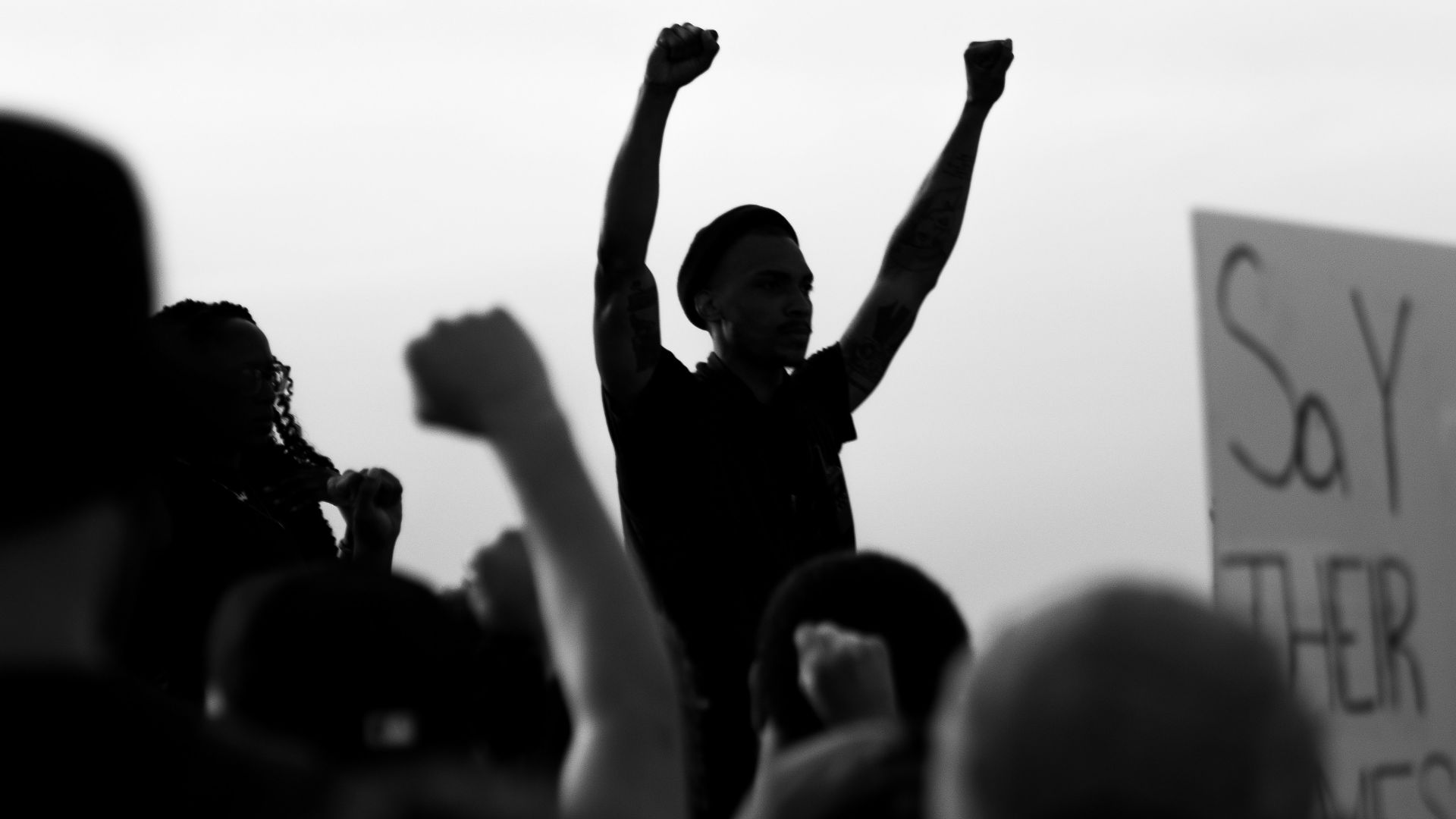 grayscale photo of people raising their hands