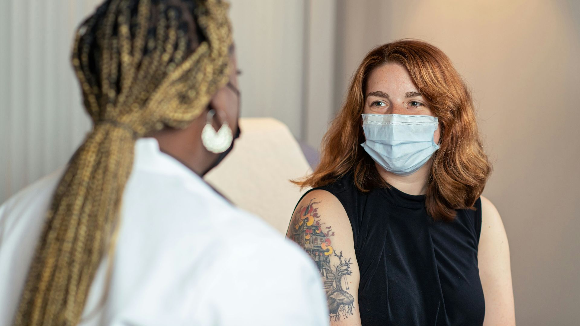 a woman with a face mask talking to another woman