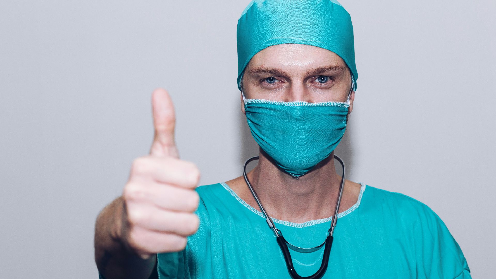 person in green crew neck long sleeve shirt wearing blue face mask